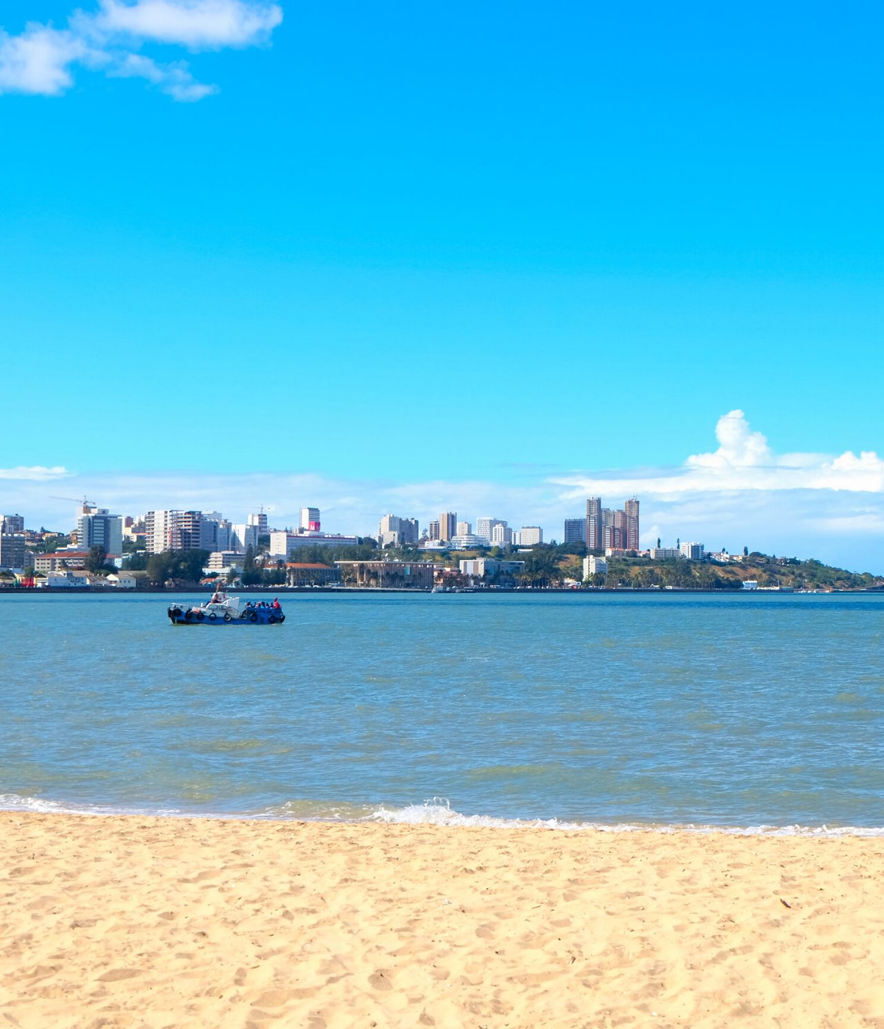 Vista sobre la ciudad de Maputo desde el otro lado del río, en una playa donde varios niños juegan con el agua