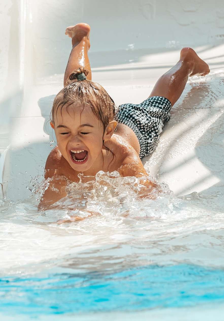 Niño sonriente deslizándose por un tobogán de agua en Slide & Splash, en el Algarve