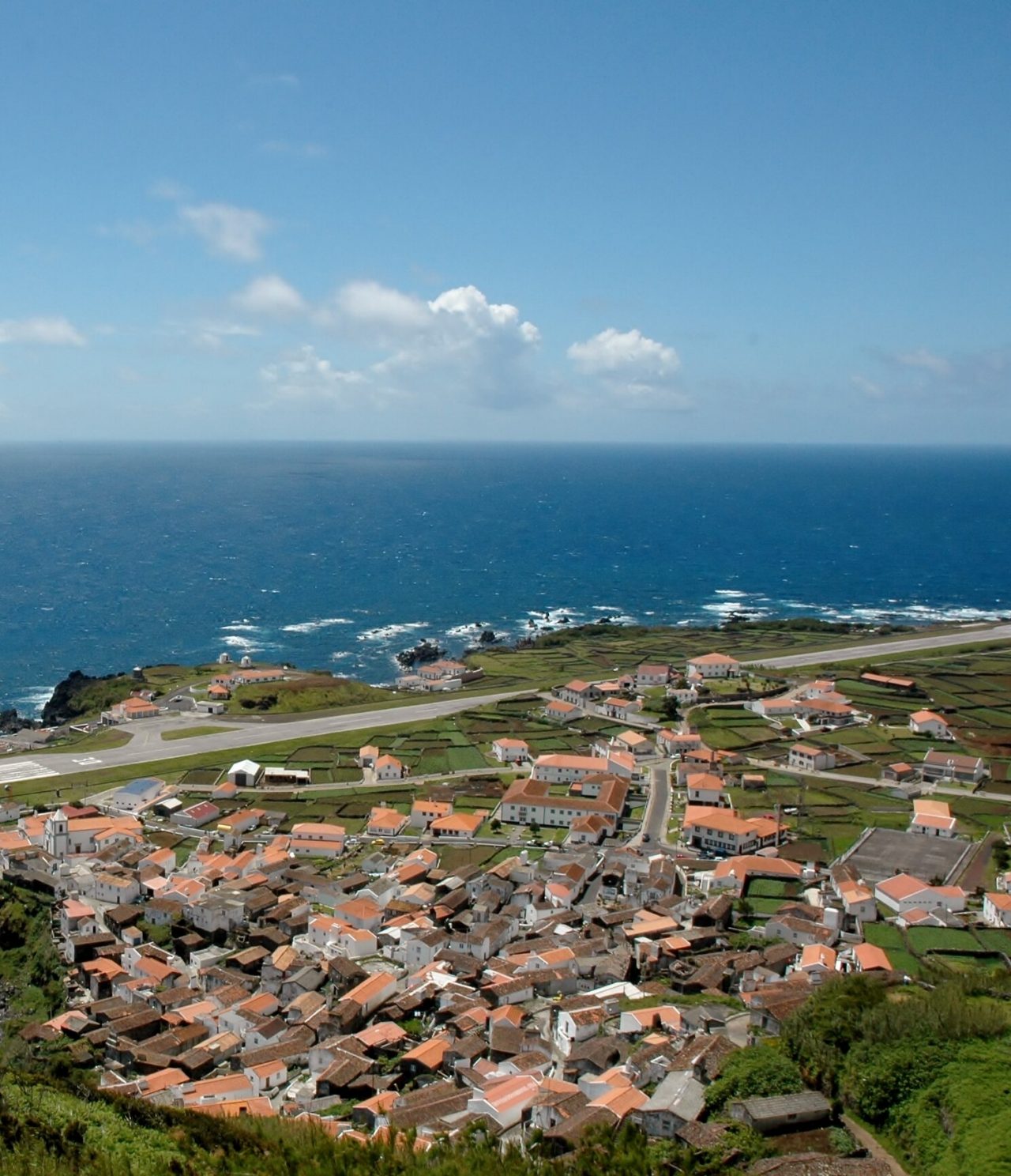 Vista aérea de la isla de Corvo, con su pista de aterrizaje, pueblo pintoresco y piscina natural, rodeada por el mar azul