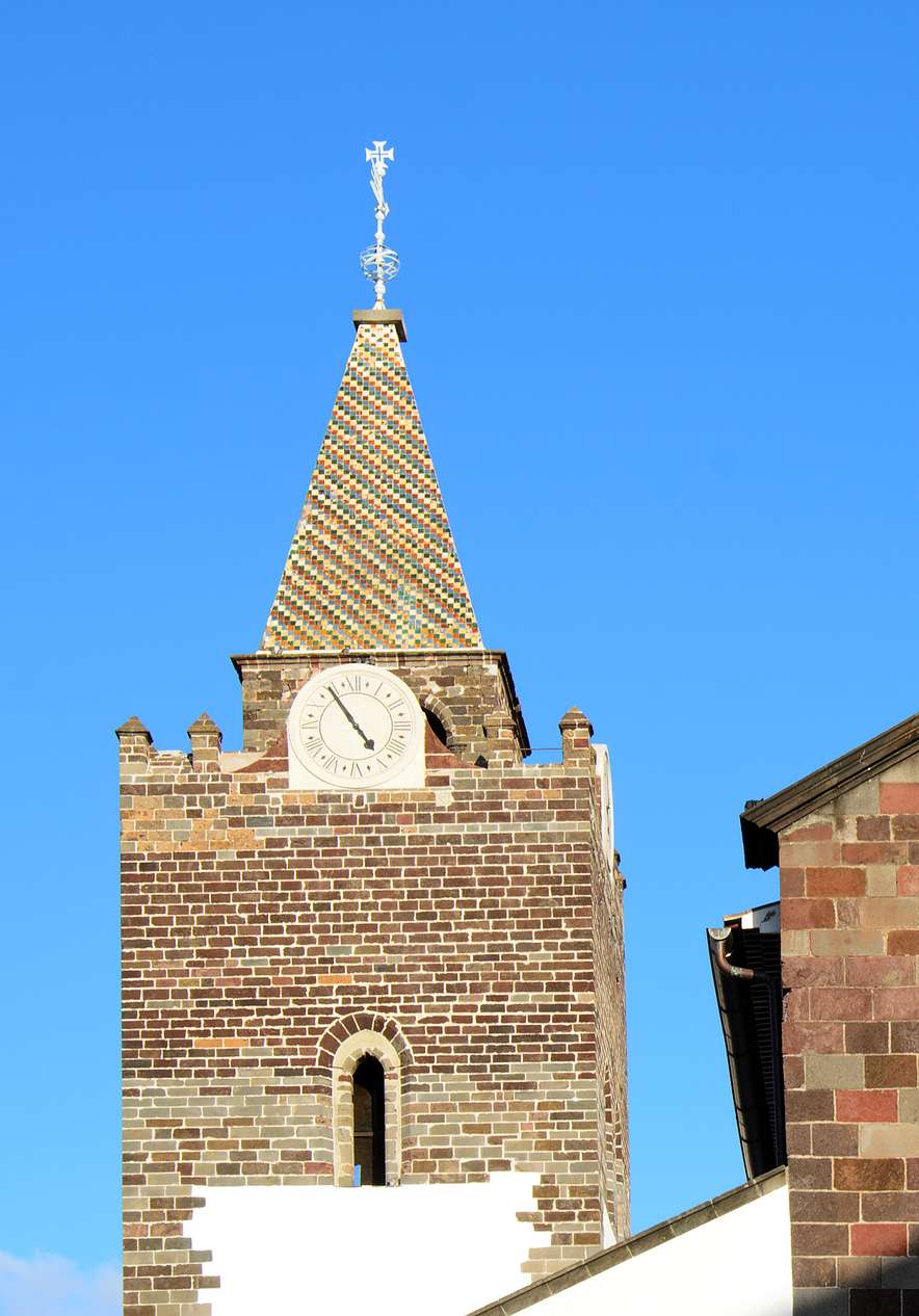 Catedral de Funchal con torre, reloj y fachada de piedra bajo cielo azul