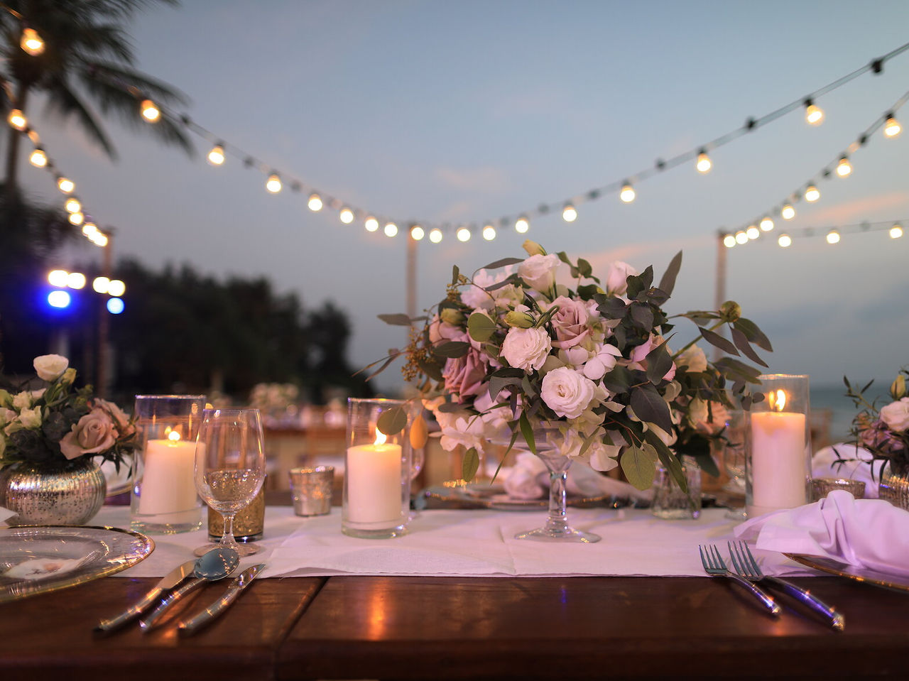 Decoración a tu gusto para tu ocasión especial, con mesas al aire libre, arreglos florales y luces colgantes