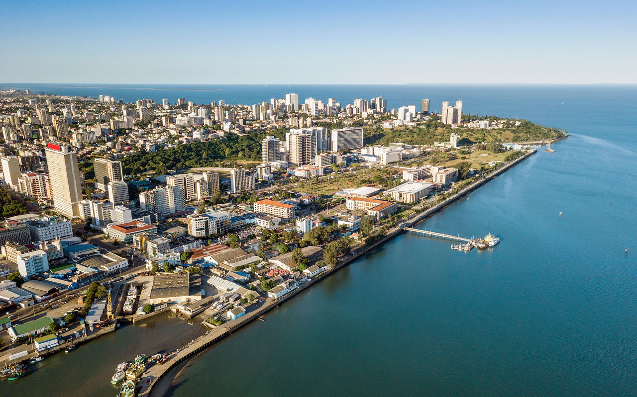 Vista aérea da cidade de Maputo, capital de Moçambique, com várias concentrações de prédios e mar em seu redor