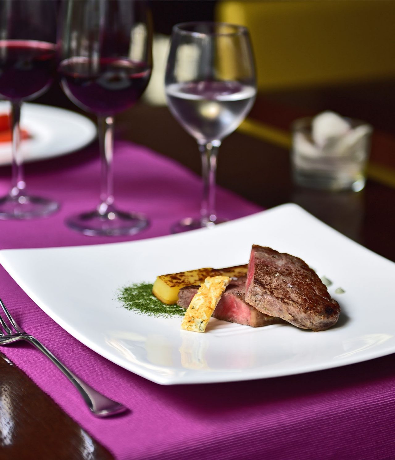 O bar Lobby, do Hotel em Barcelona, tem um prato elegante com carne e fruta, e um copo de vinho e água