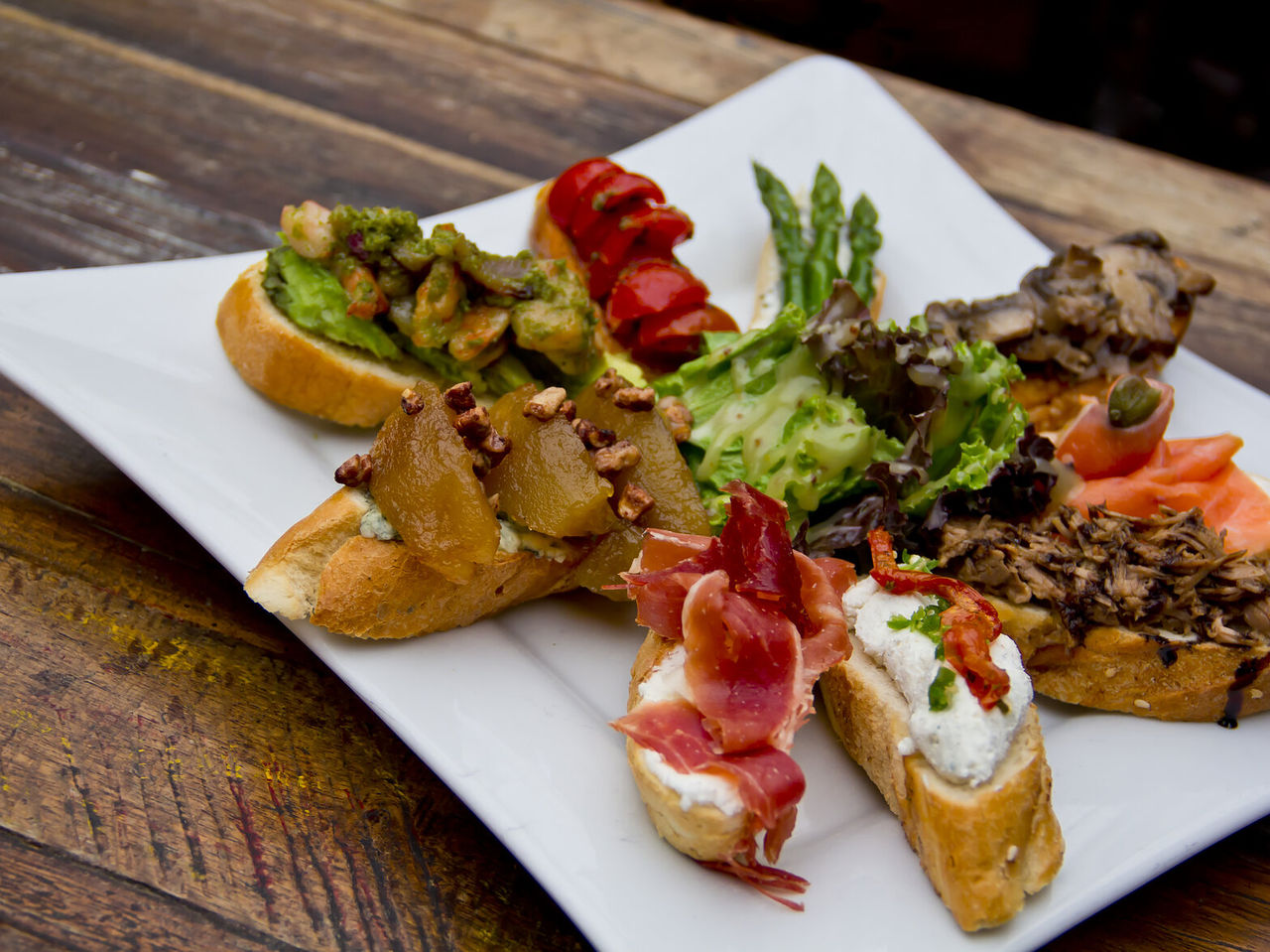 Prato com bocadillos, tapas típicas espanholas, com vários recheios por cima do pão, desde presunto a queijo e tomate