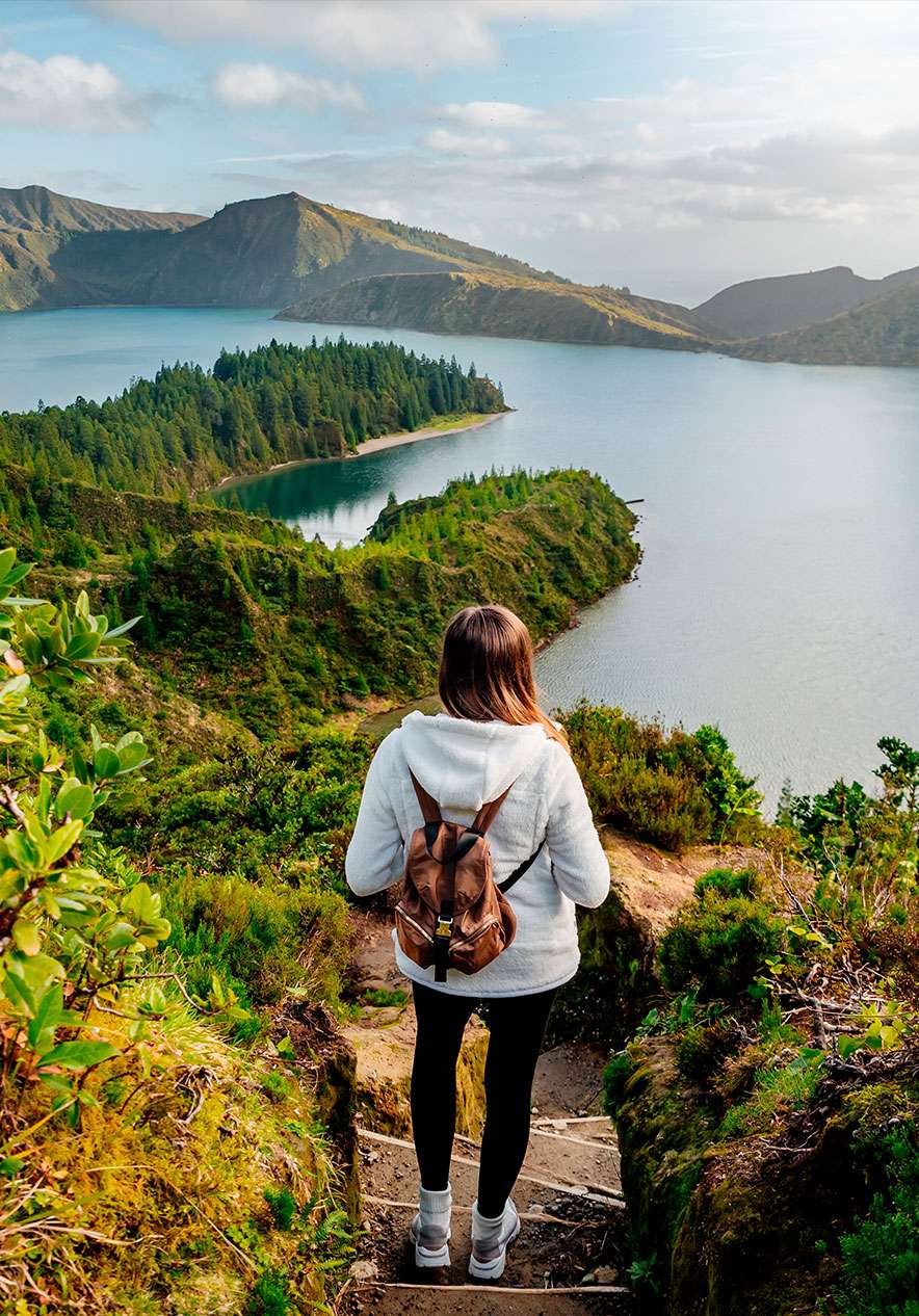 Rapariga com mochila às costas, avança pelas escadas que dão acesso à magnífica Lagoa do Fogo, circundada por natureza