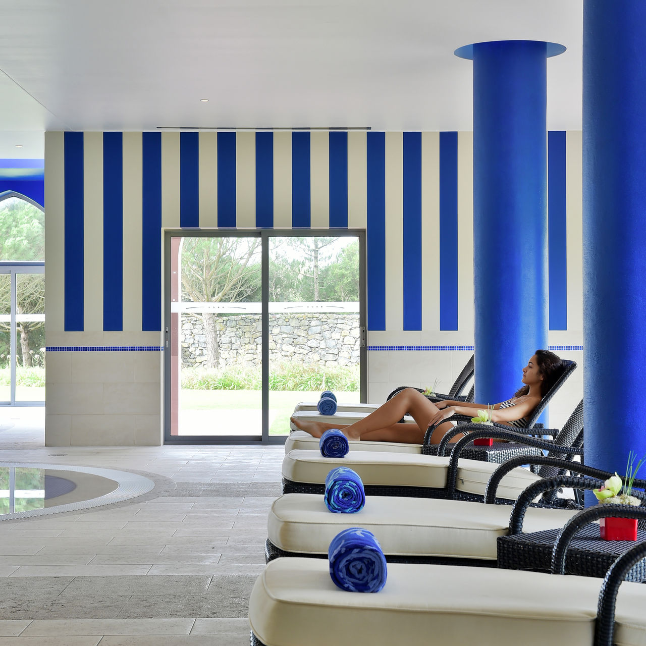 Piscina interior do Pestana Sintra Golf, Hotel 4 Estrelas em Sintra, com espreguiçadeiras almofadadas e toalhas azuis