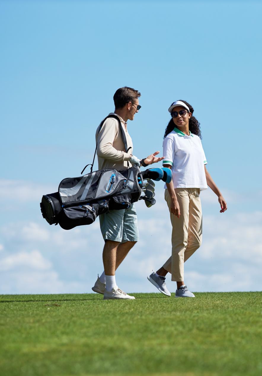 Casal a carregar tacos de golfe, num campo de golfe na ilha do Porto Santo, com céu azul