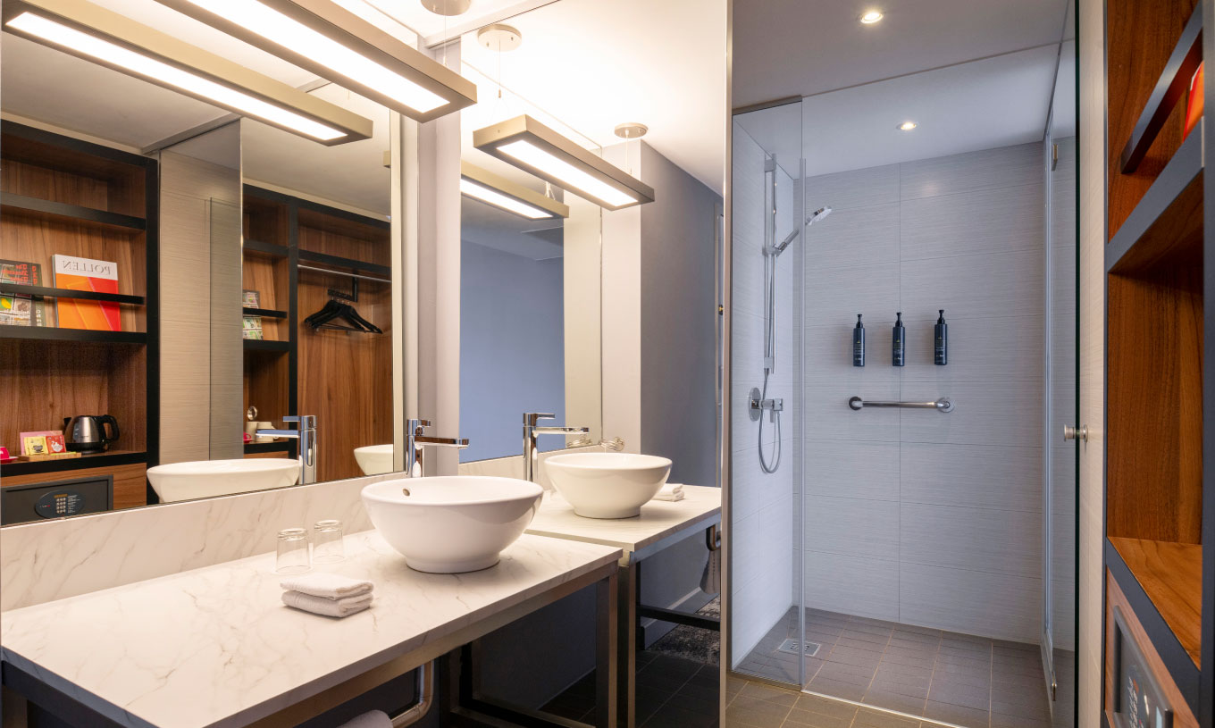 The Family at Pestana Brussels Schuman has a bathroom with a washbasin, a large mirror, and a shower