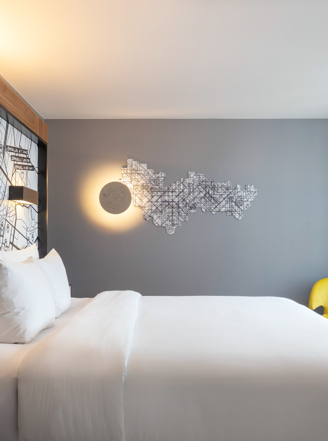 The Standard King at Pestana Brussels Schuman has a double bed with white sheets and a wall lamp