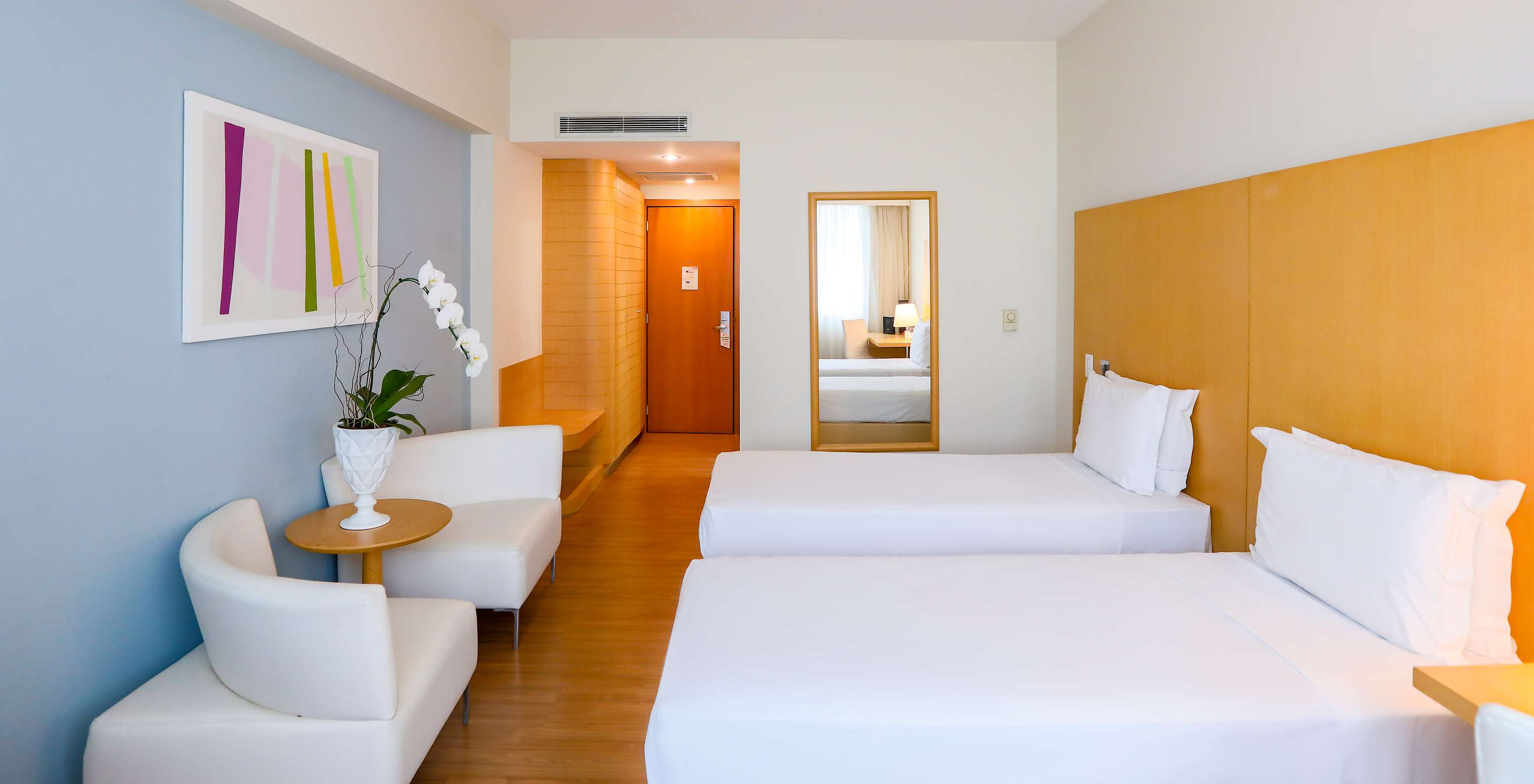 The Twin Standard at Pestana Curitiba has two single beds with sofas at the foot of the bed and a small table with flowers