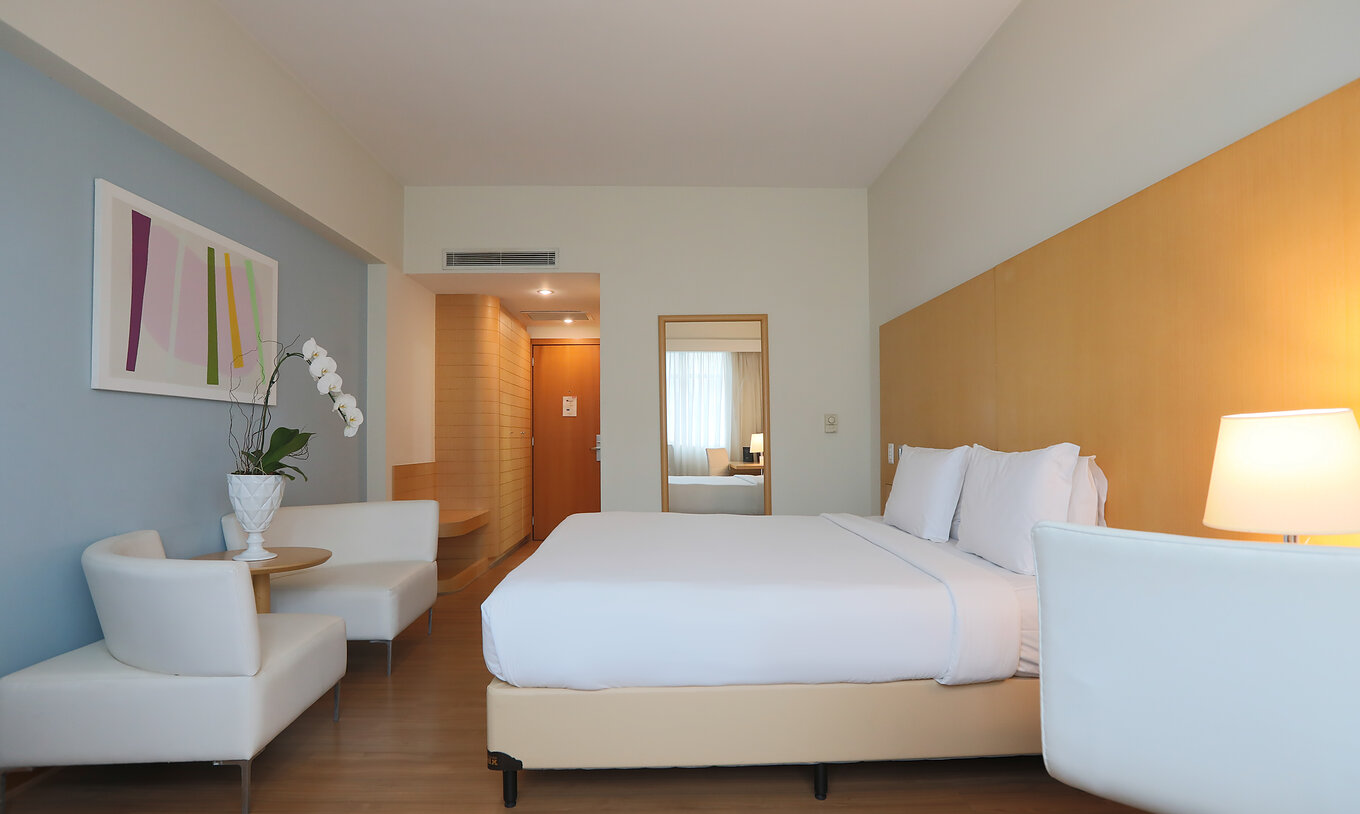 The Queen Standard at Pestana Curitiba has a double bed and two single sofas at the foot of the bed