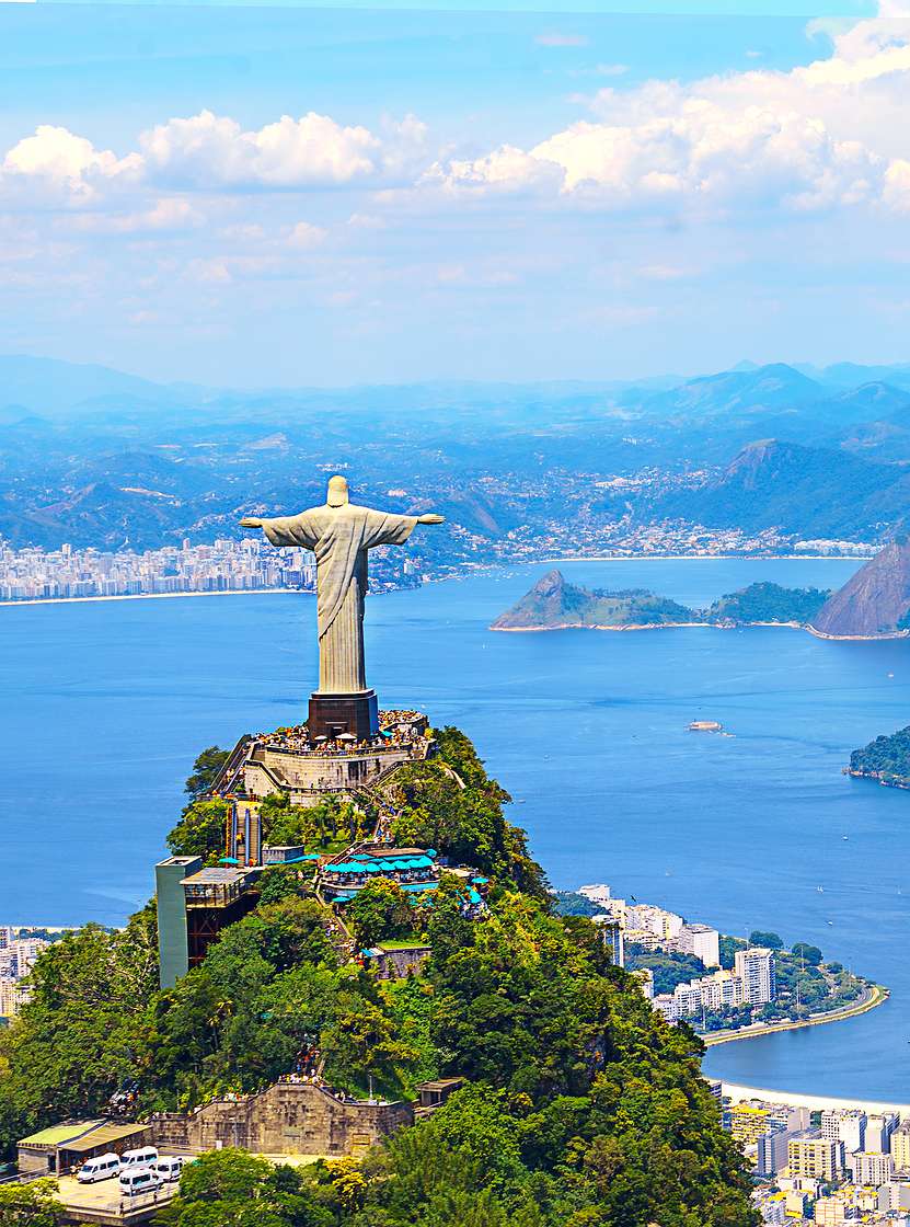 Iconic statue of Christ the Redeemer in Rio de Janeiro, with the city, ocean, and beach in the background