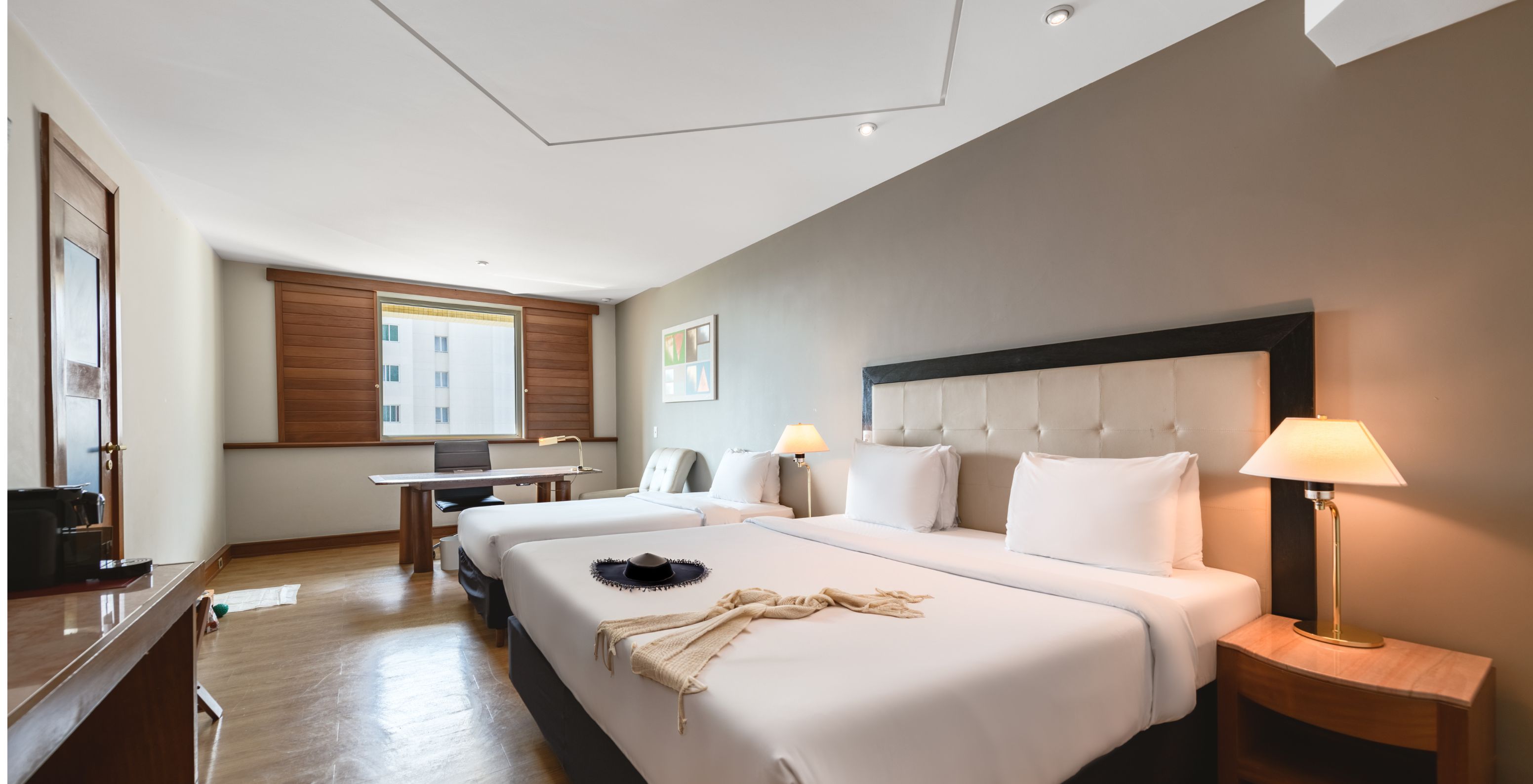The Deluxe at Pestana São Paulo has a double bed, two bedside tables, a desk, and a window