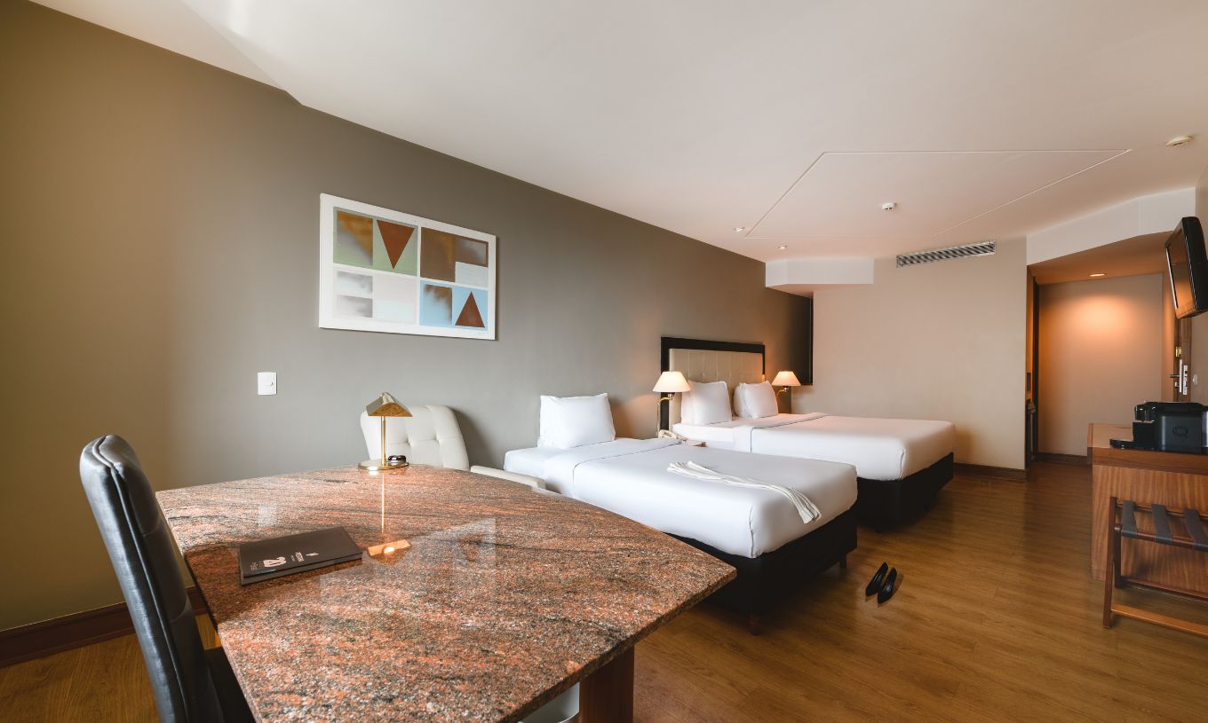 The Deluxe at Pestana São Paulo has a stone desk, a double bed, and a single bed