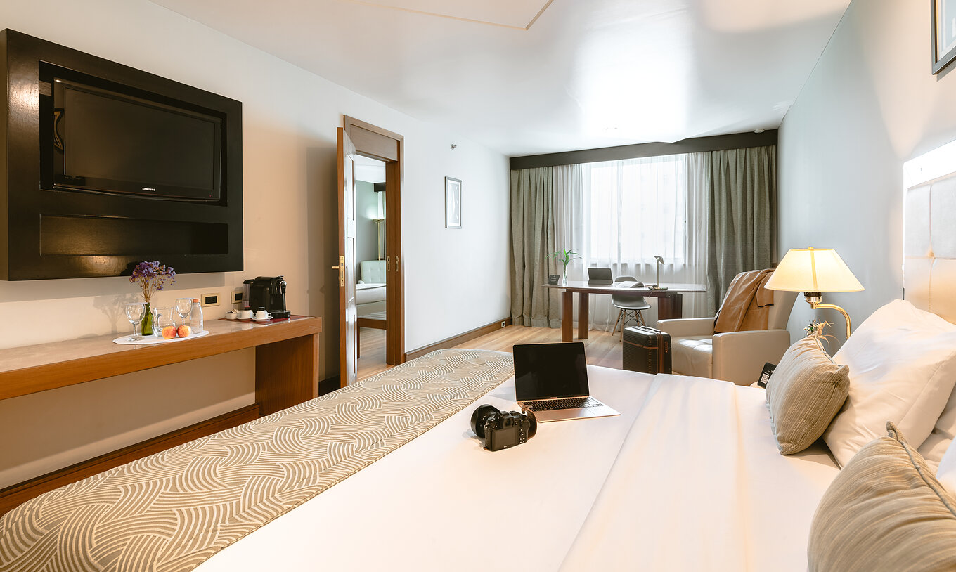 The Executive Suite of Pestana São Paulo has a room with a double bed, television, armchair, and a desk