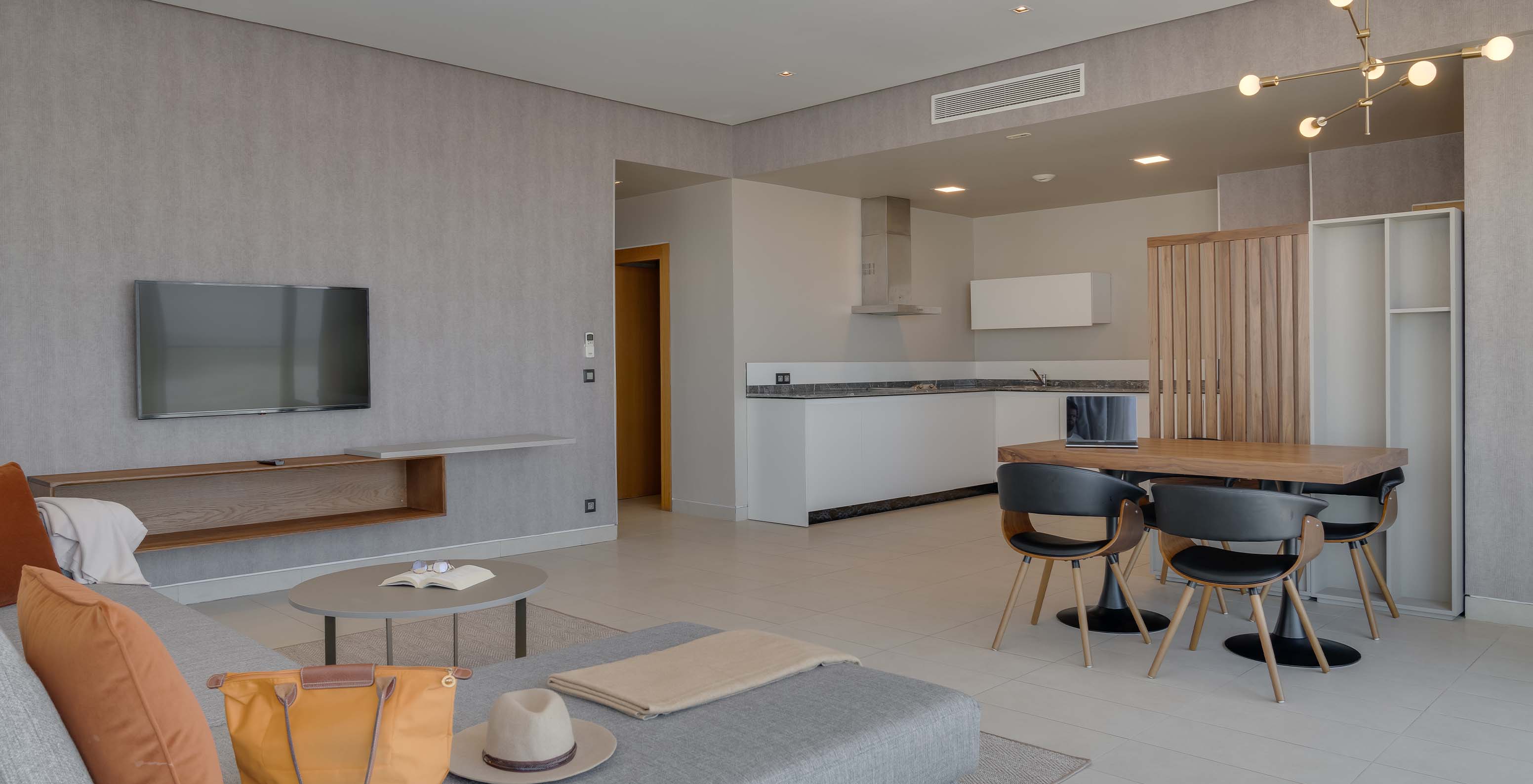 The Family Corniche Suite at Pestana Casablanca has a spacious living room with a sofa, TV, dining table, and kitchenette