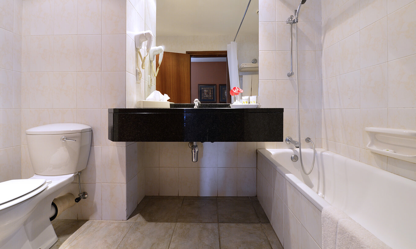 The Executive Double of Pestana Rovuma has a bathroom with bathtub with shower, sink with mirror, and a toilet