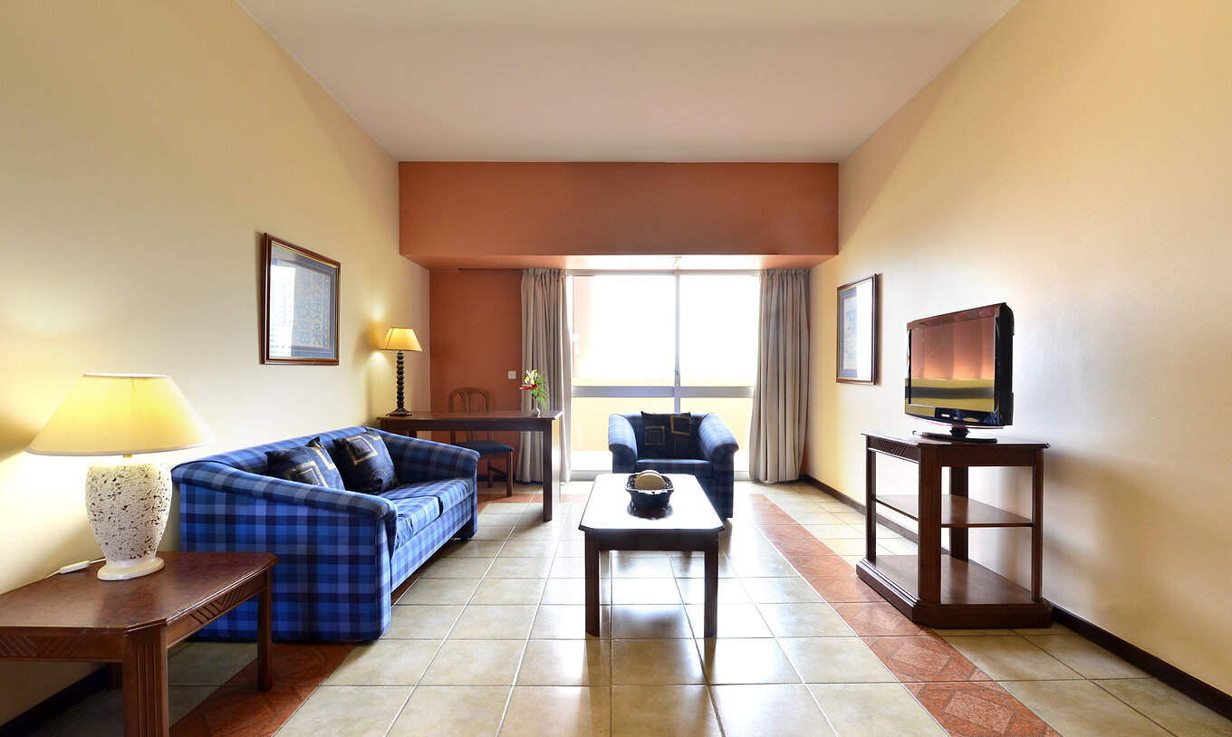 The Executive Suite of Pestana Rovuma has a living room with sofa, television, and a large window with balcony