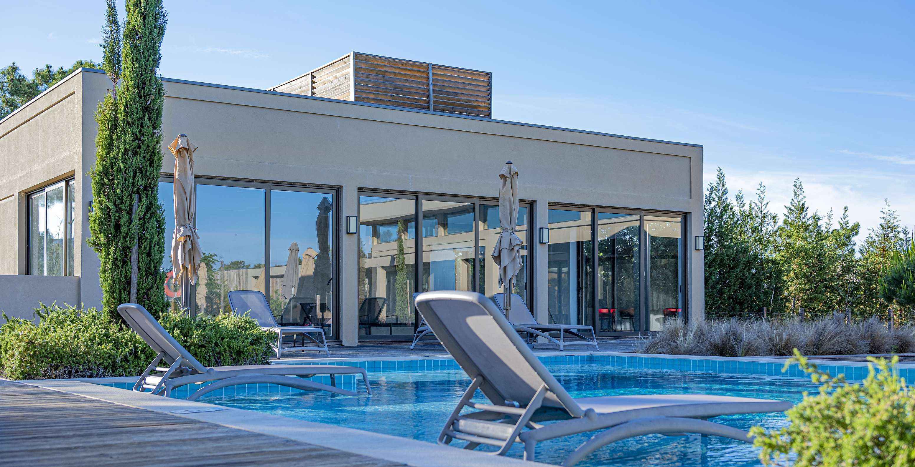 Outdoor pool at Pestana Tróia Eco Resort with two sun loungers in the water, where you can relax