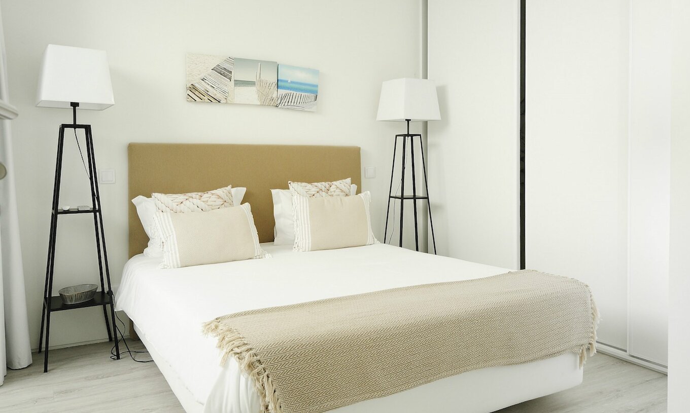 The Green T3 Villa of Pestana Tróia Eco Resort has a double bed with two bedside tables and a beige bedspread