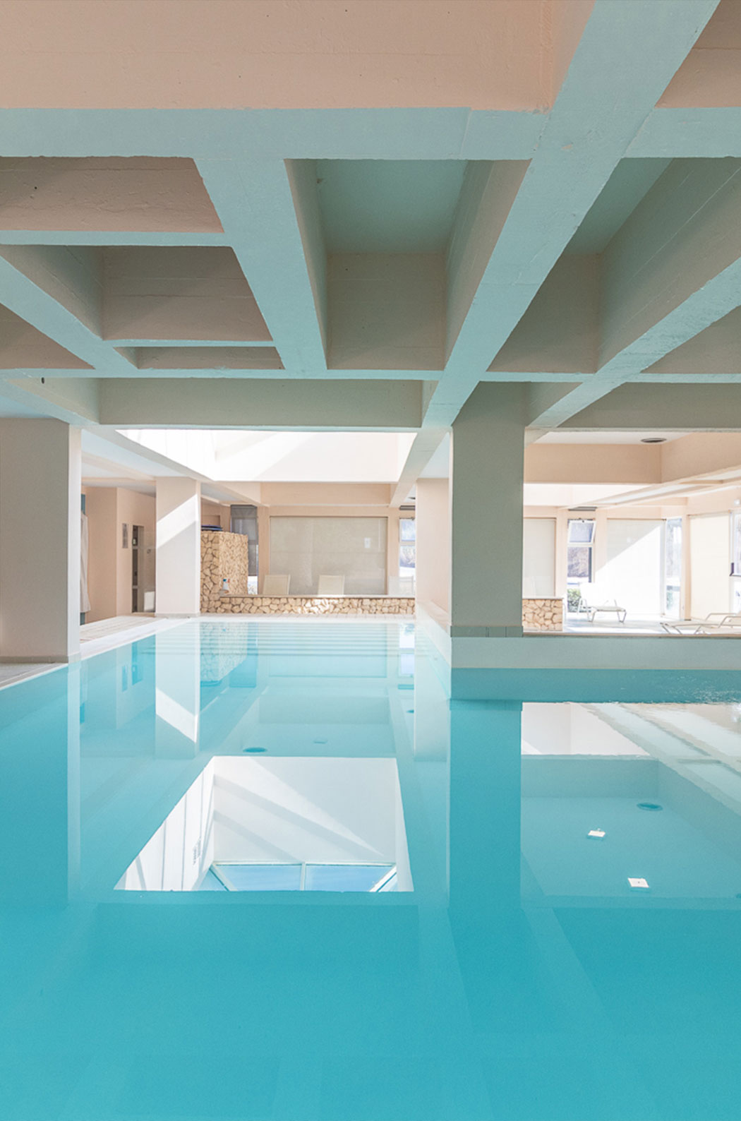 Indoor pool with natural light and sun loungers in the seafront aparthotel