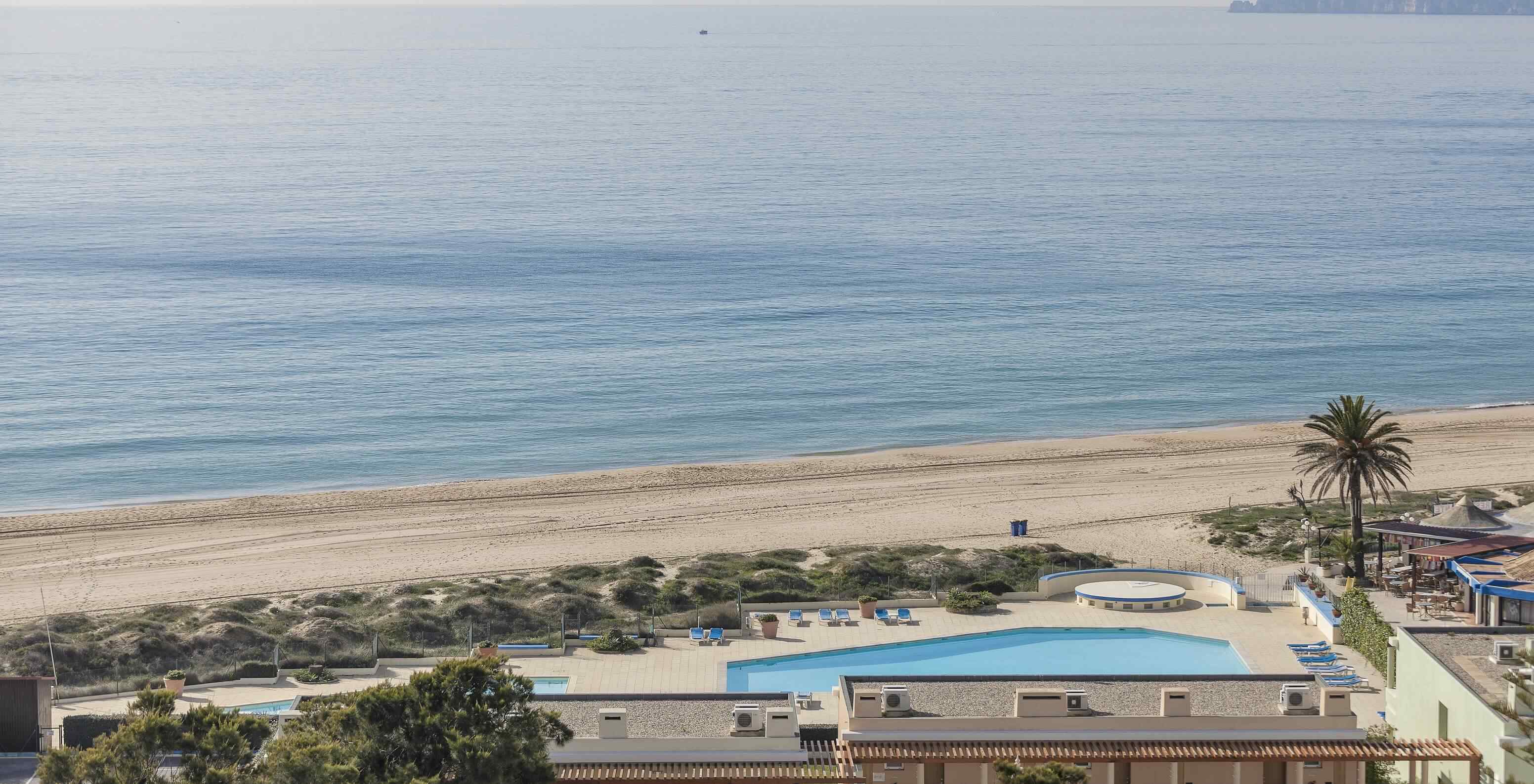 Alvor Beach in Algarve has golden sand, crystal-clear water, a boardwalk, and dunes
