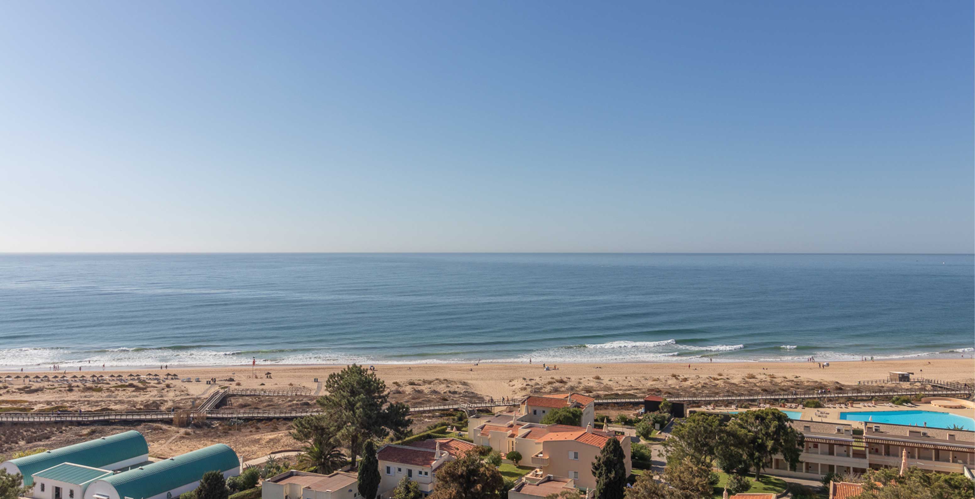 Alvor Beach in Algarve with golden sand, clear water, boardwalk, and dunes