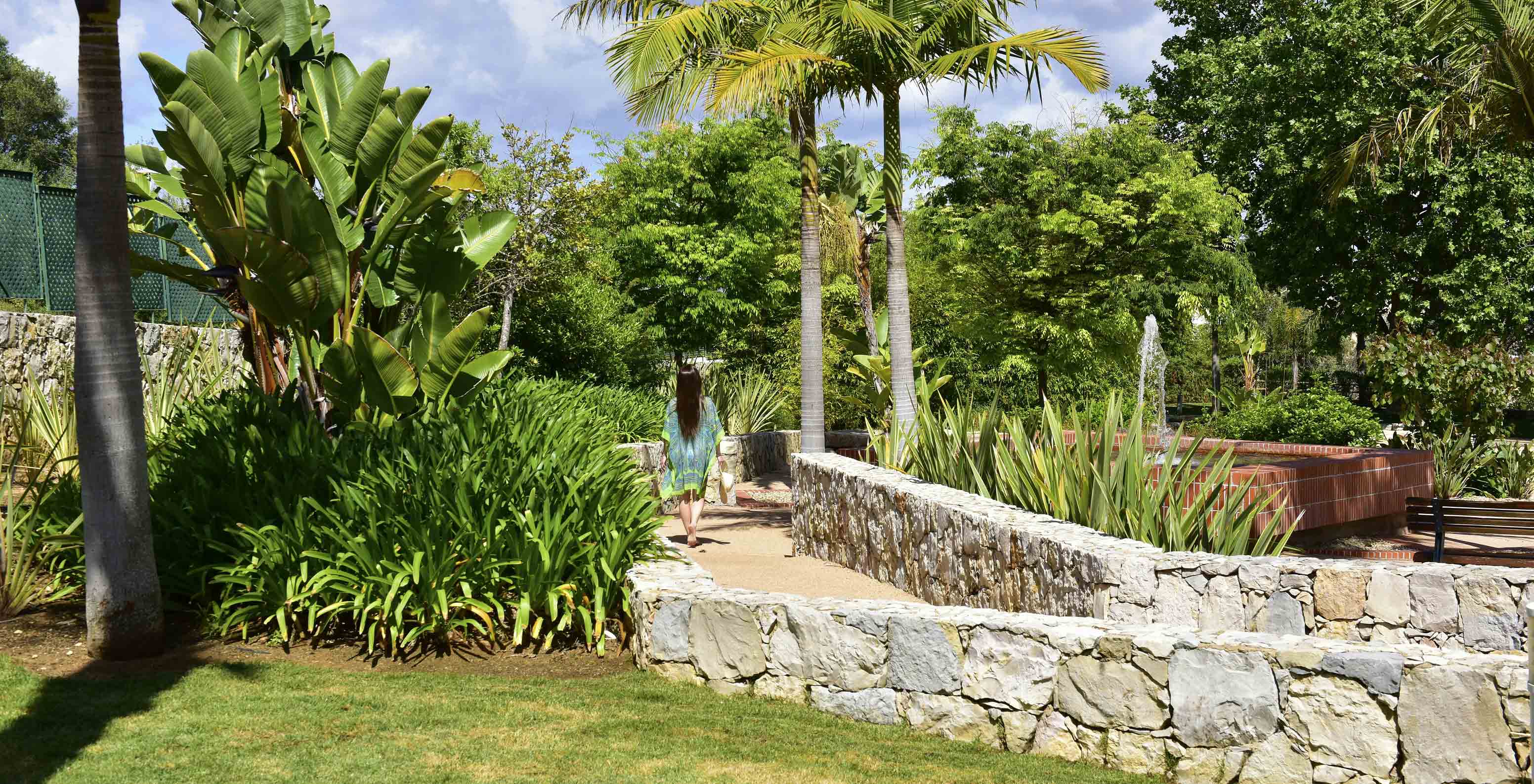 Guest strolling in the garden with tropical vegetation at Pestana Alvor Park, 4-star Aparthotel in Alvor with Pool