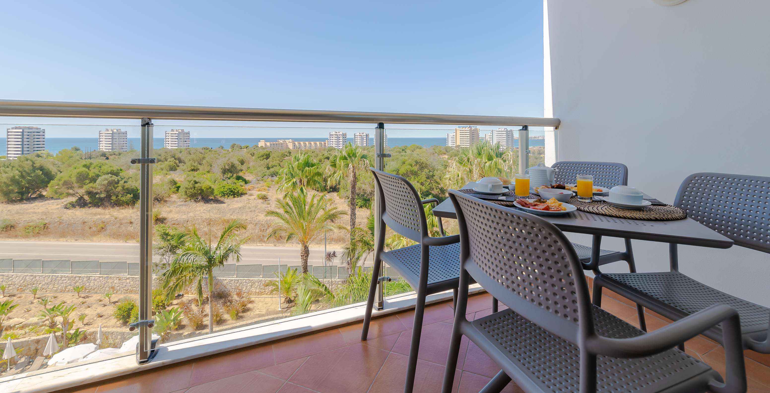 The T1 - with 1 Superior Bedroom at Pestana Alvor Park has a balcony with a table and chairs overlooking the sea