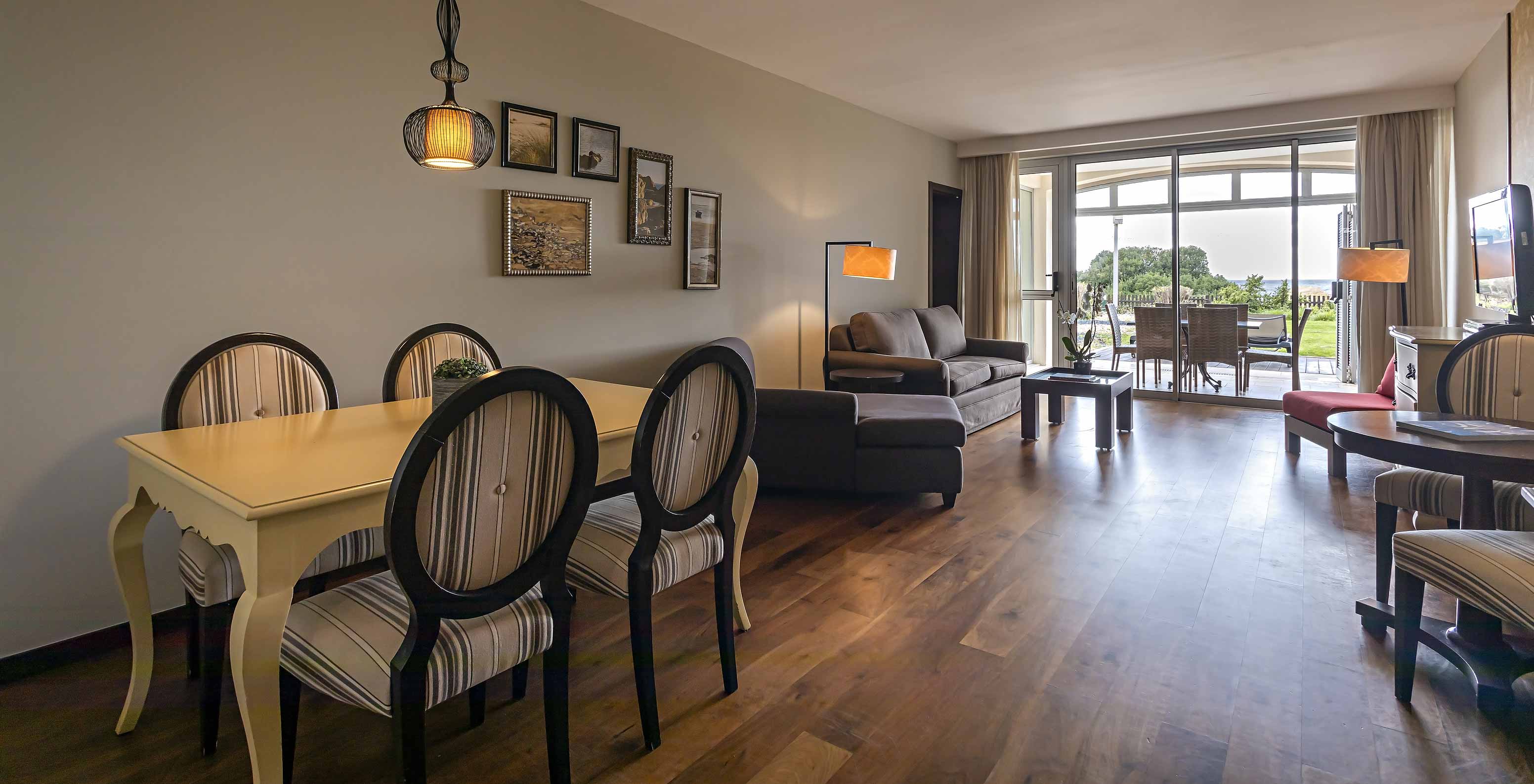 The Cliff Suite T2 at Pestana Alvor Praia has a living room with two sofas, a television, a dining table, and a porch