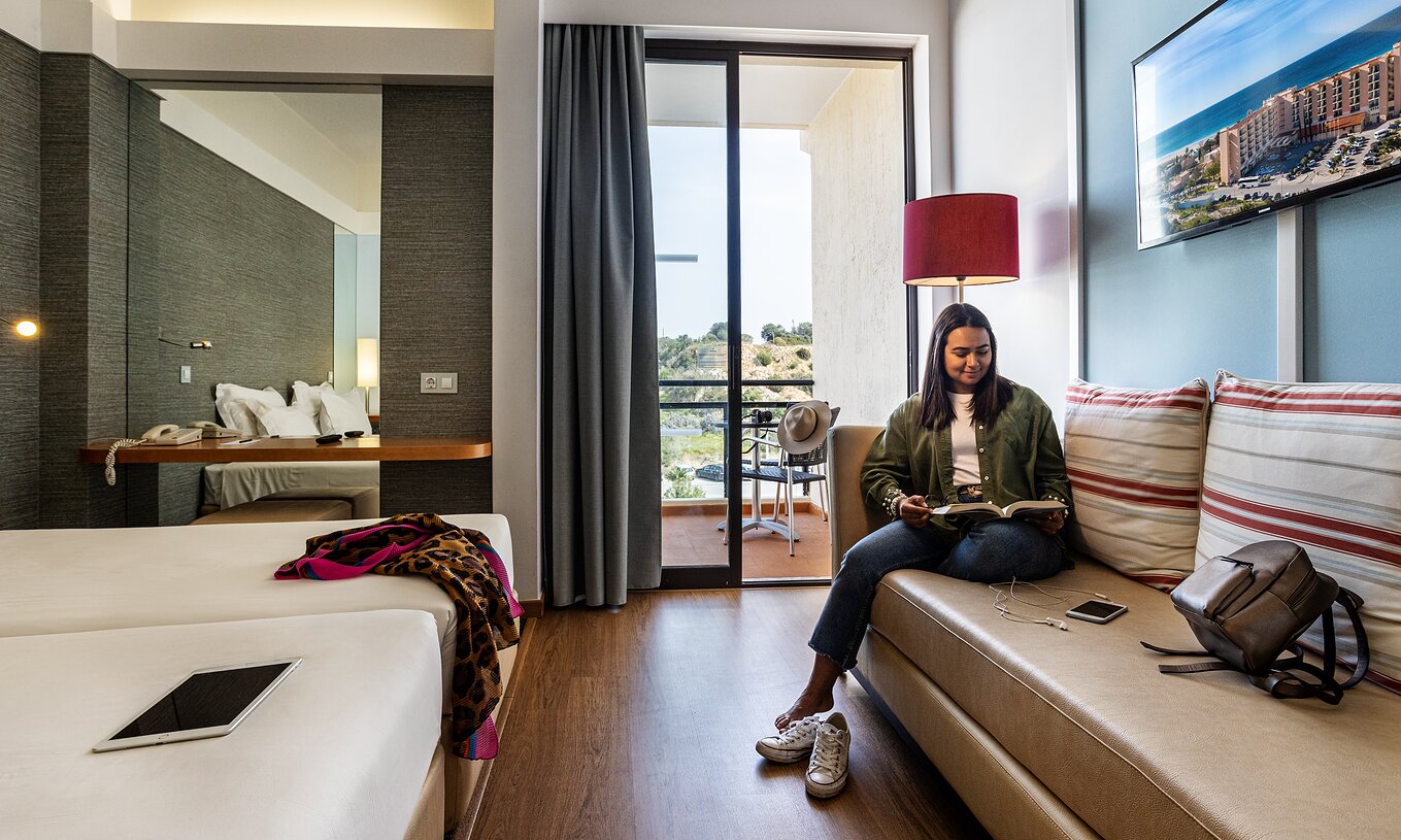 The Deluxe Ground View at Pestana Dom João II includes a sofa, a mirror, and a balcony overlooking the garden