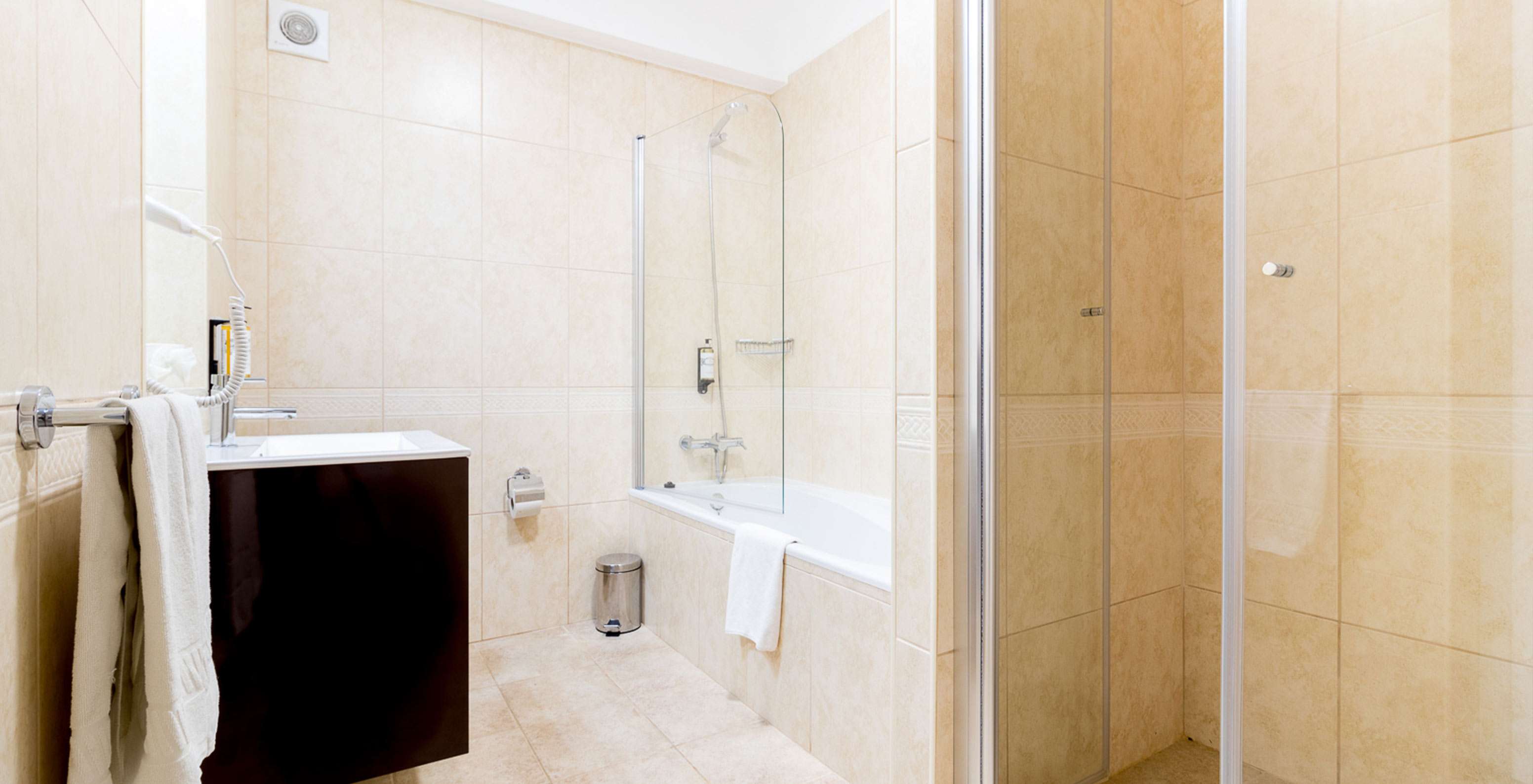 The one-bedroom apartment at Pestana Gramacho has a bright bathroom with bathtub, shower, and modern sink