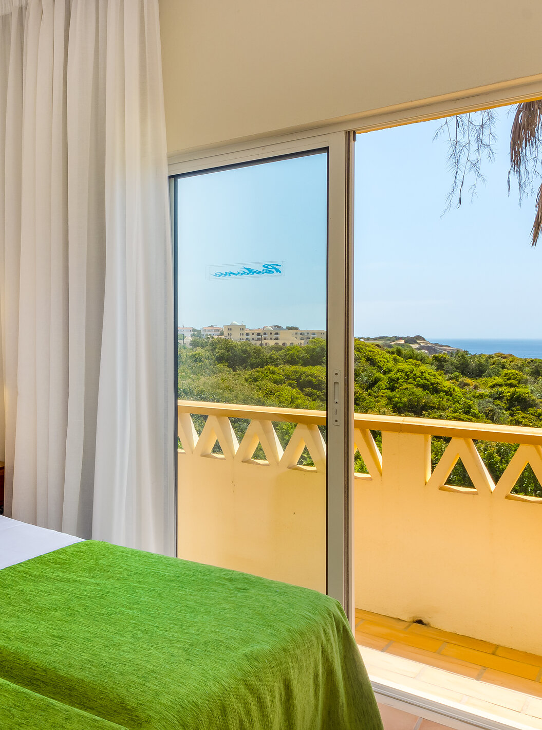 The T2 Apartment Superior do Pestana Palm Gardens has two beds together with a green bedspread and a balcony with sea view