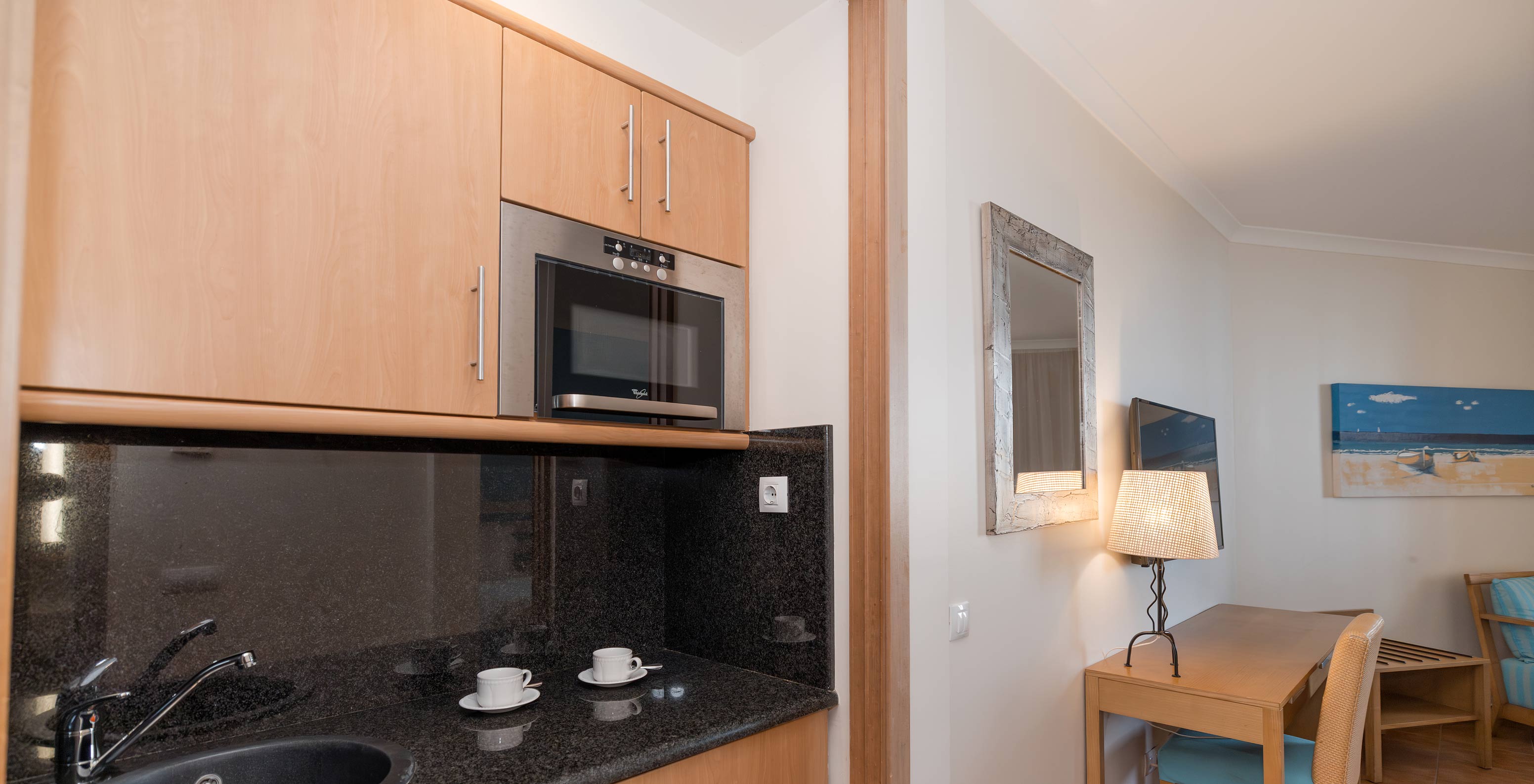 The Deluxe Garden View at Pestana Viking has a desk and a small kitchen with microwave and cabinets