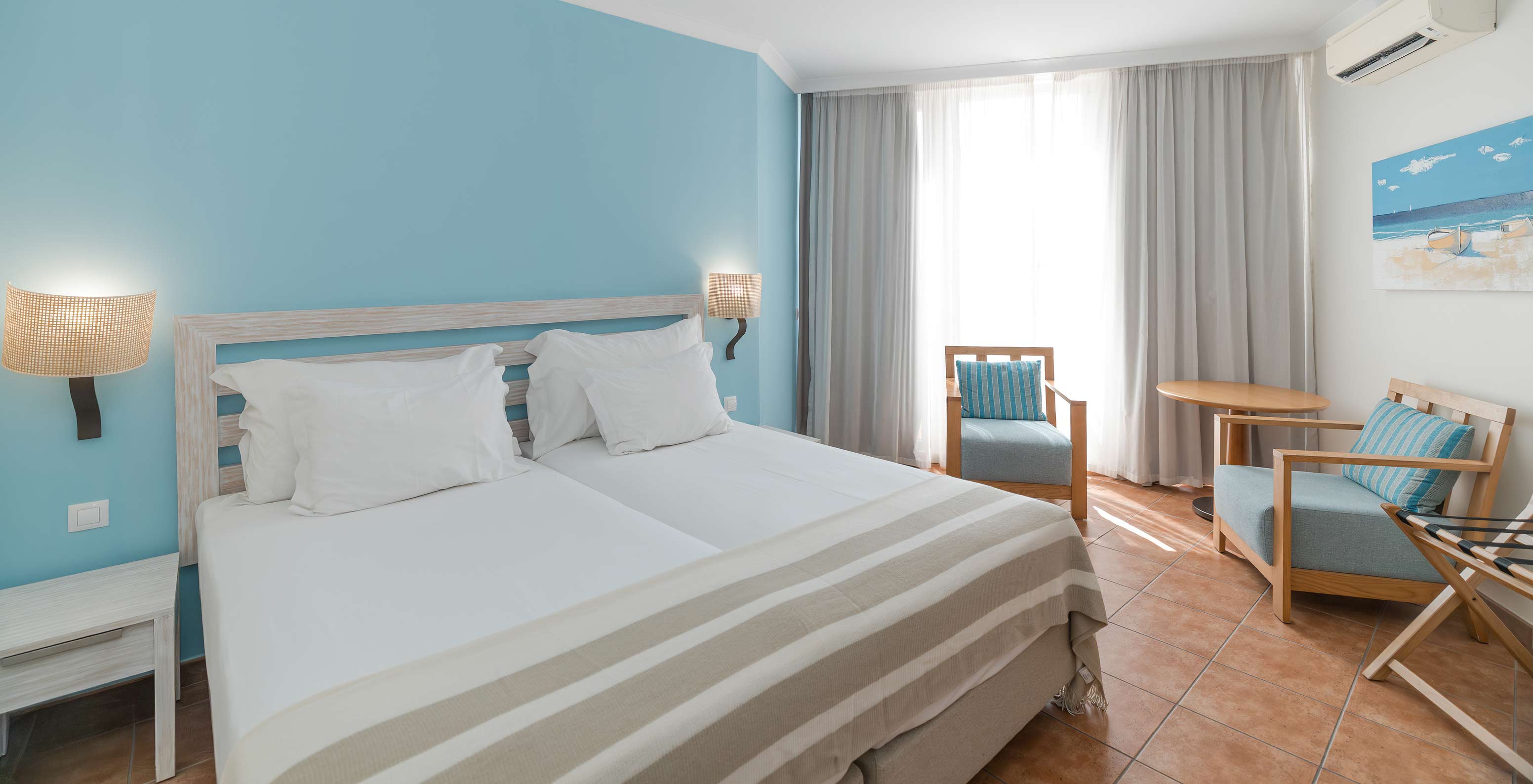 The Deluxe Sea View at Pestana Viking has two beds, bedside table, two armchairs and air conditioning