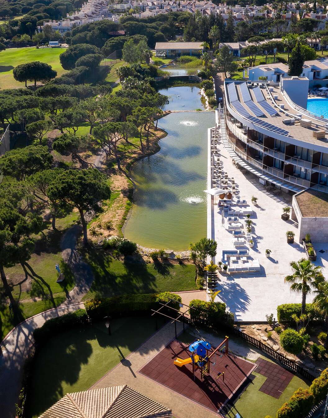 View of Pestana Vila Sol - Vilamoura, a 5-star hotel in Vilamoura with a pool and surrounded by a lake and green vegetation