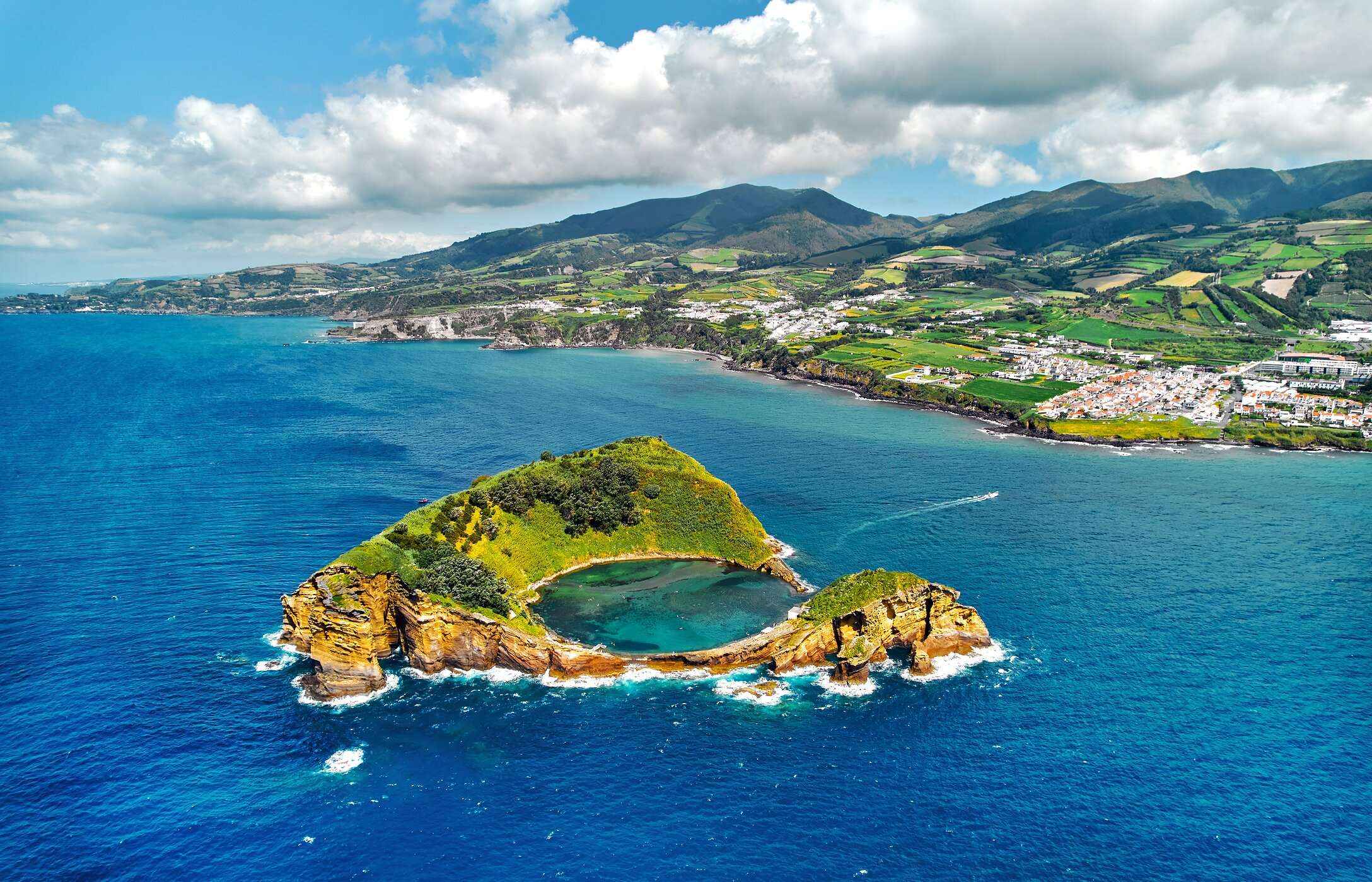 Panoramic view of Vila Franca do Campo, with a ring-shaped islet in the ocean, and green hills in the background