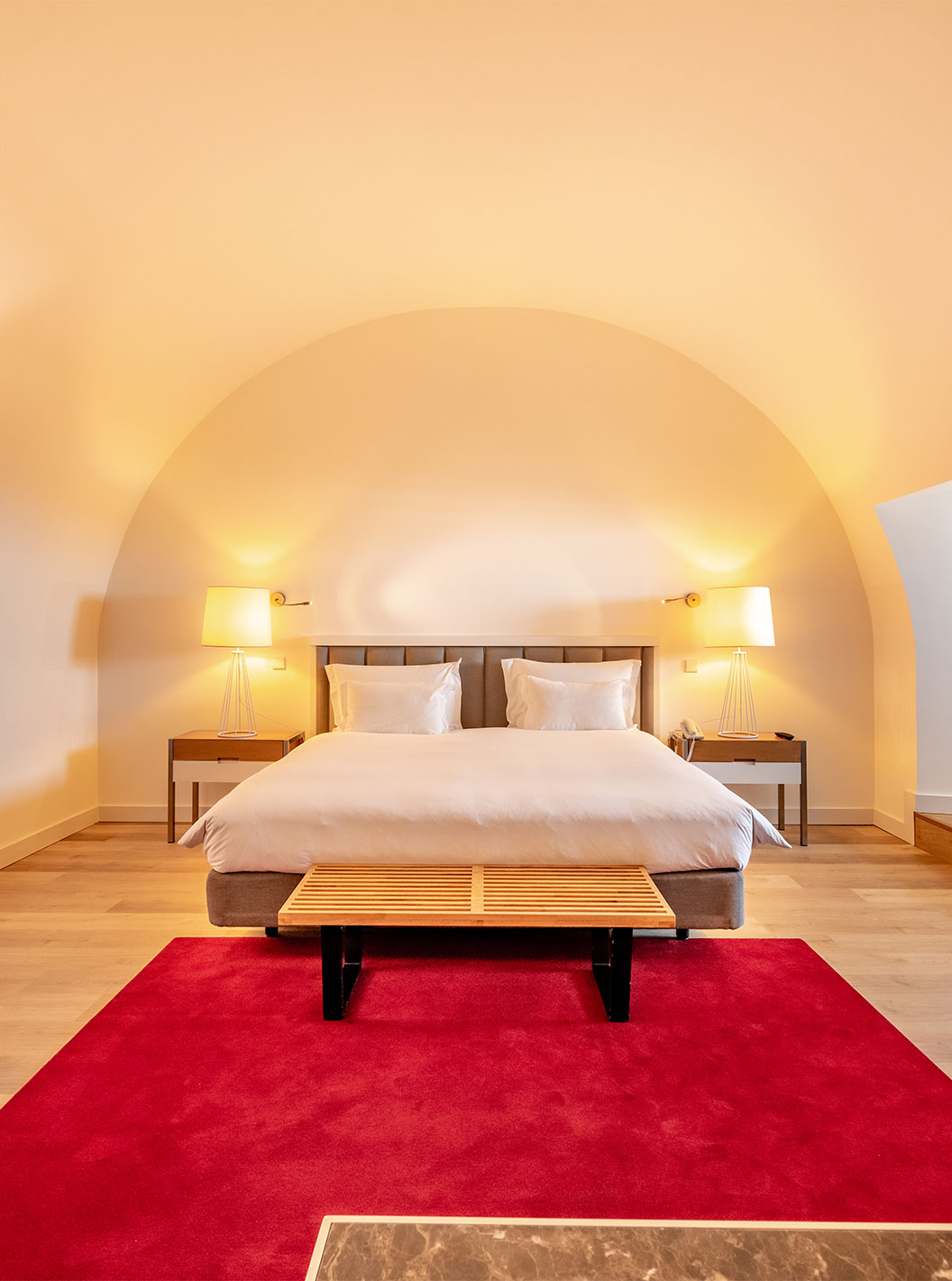 The Junior Family Suite at Pestana Cidadela Cascais has a double bed with a bench at the foot and a red carpet