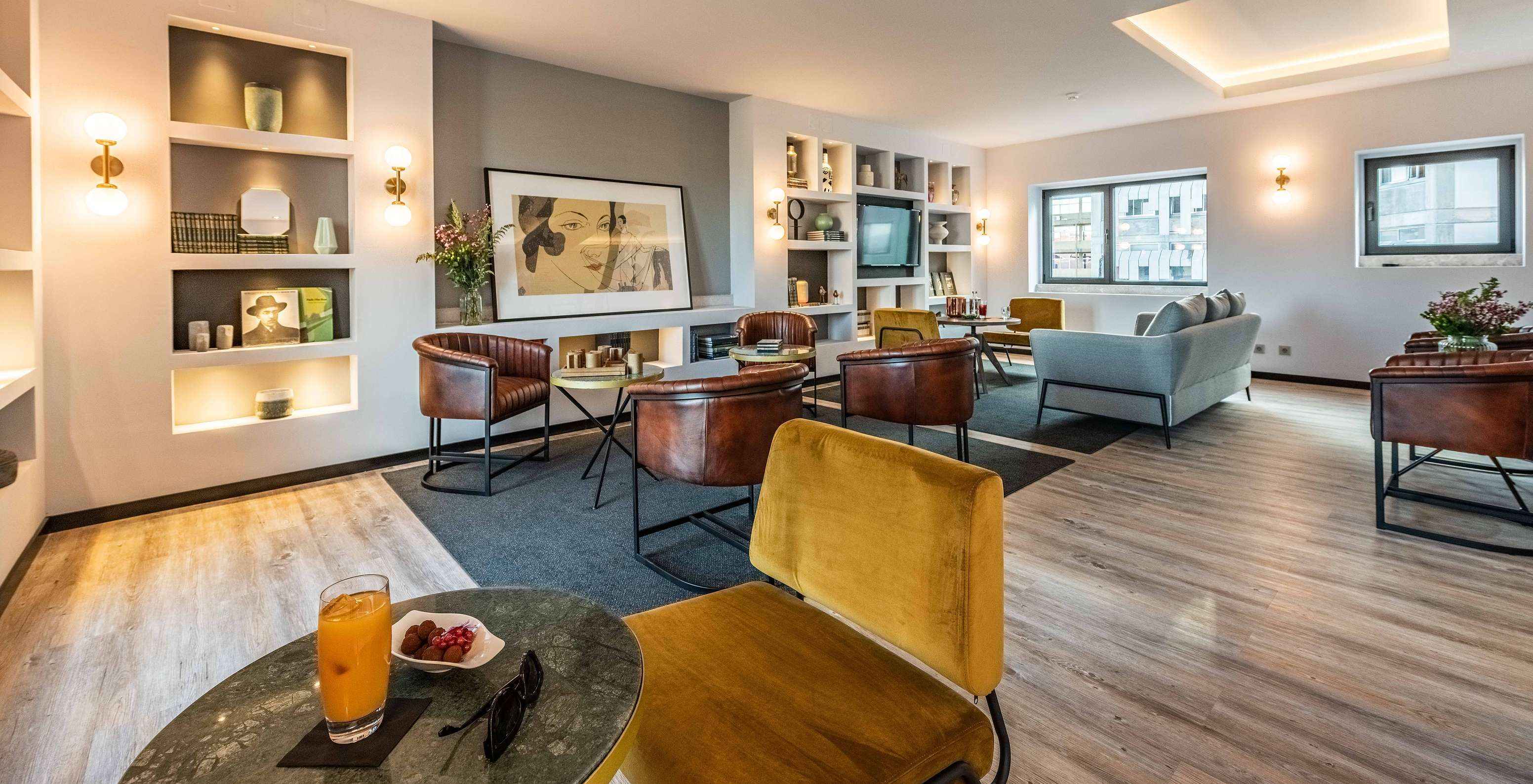 Lounge with sofas, chairs, tables, paintings, television, rugs and decor items with windows overlooking the city