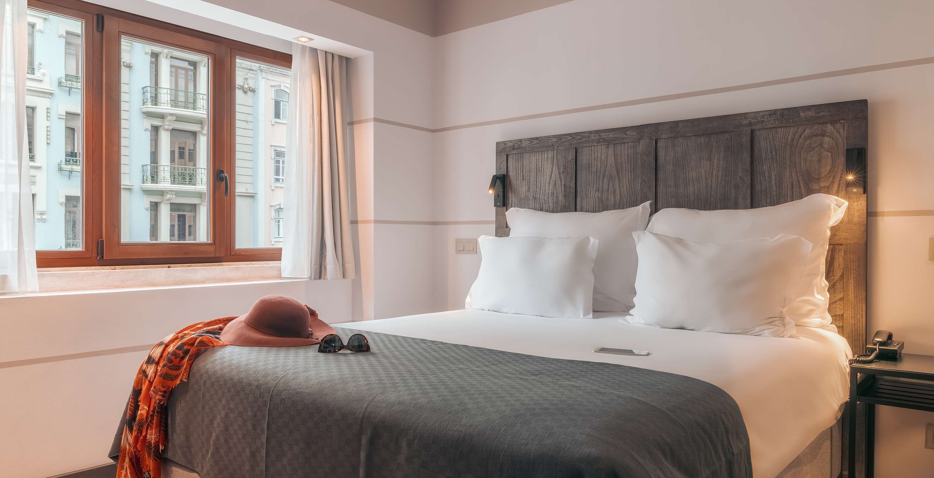 The Double Classic Room at Pestana Lisboa Vintage has a double bed with headboard and gray blanket and a wooden window