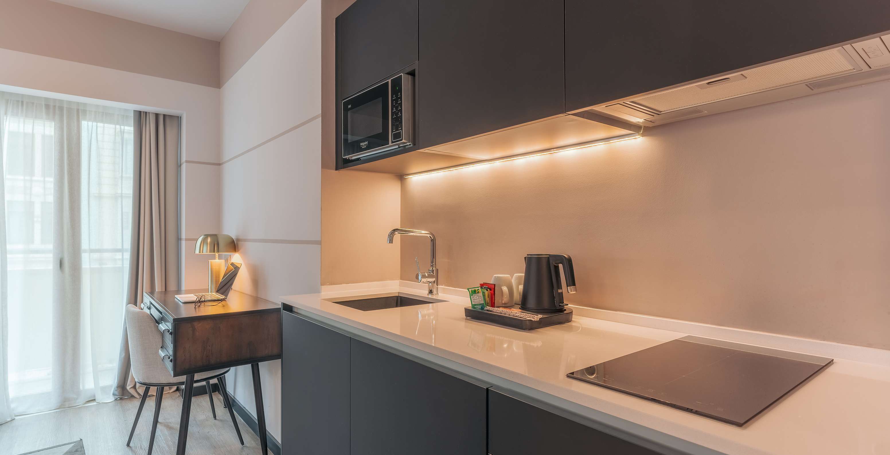 The Junior Suite at Pestana Lisboa Vintage has a kitchen unit with stove, microwave and a desk with chair