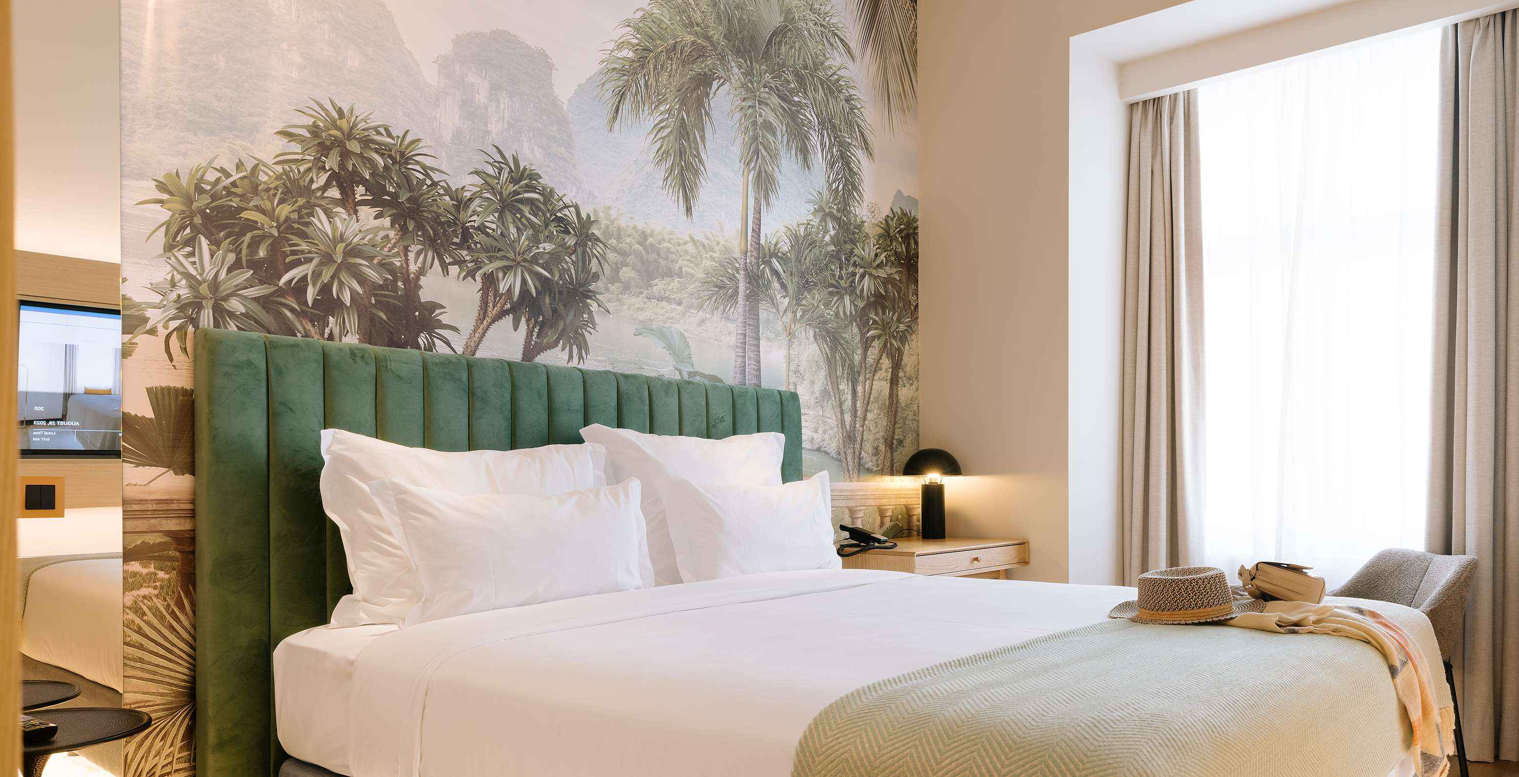 The Superior Plus Room at the Pestana Rua Augusta Lisbon has a double bed, palm tree wallpaper and a window with curtains