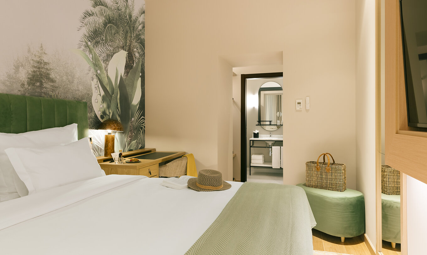 The Comfort Interior of Pestana Rua Augusta Lisboa has a double bed with a green headboard and palm wallpaper
