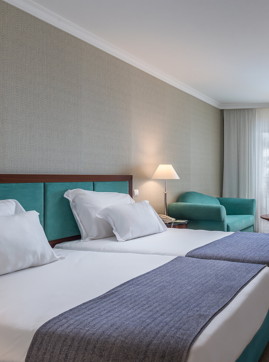 The Family Room at Pestana Grand has two single beds, TV and armchair with coffee table