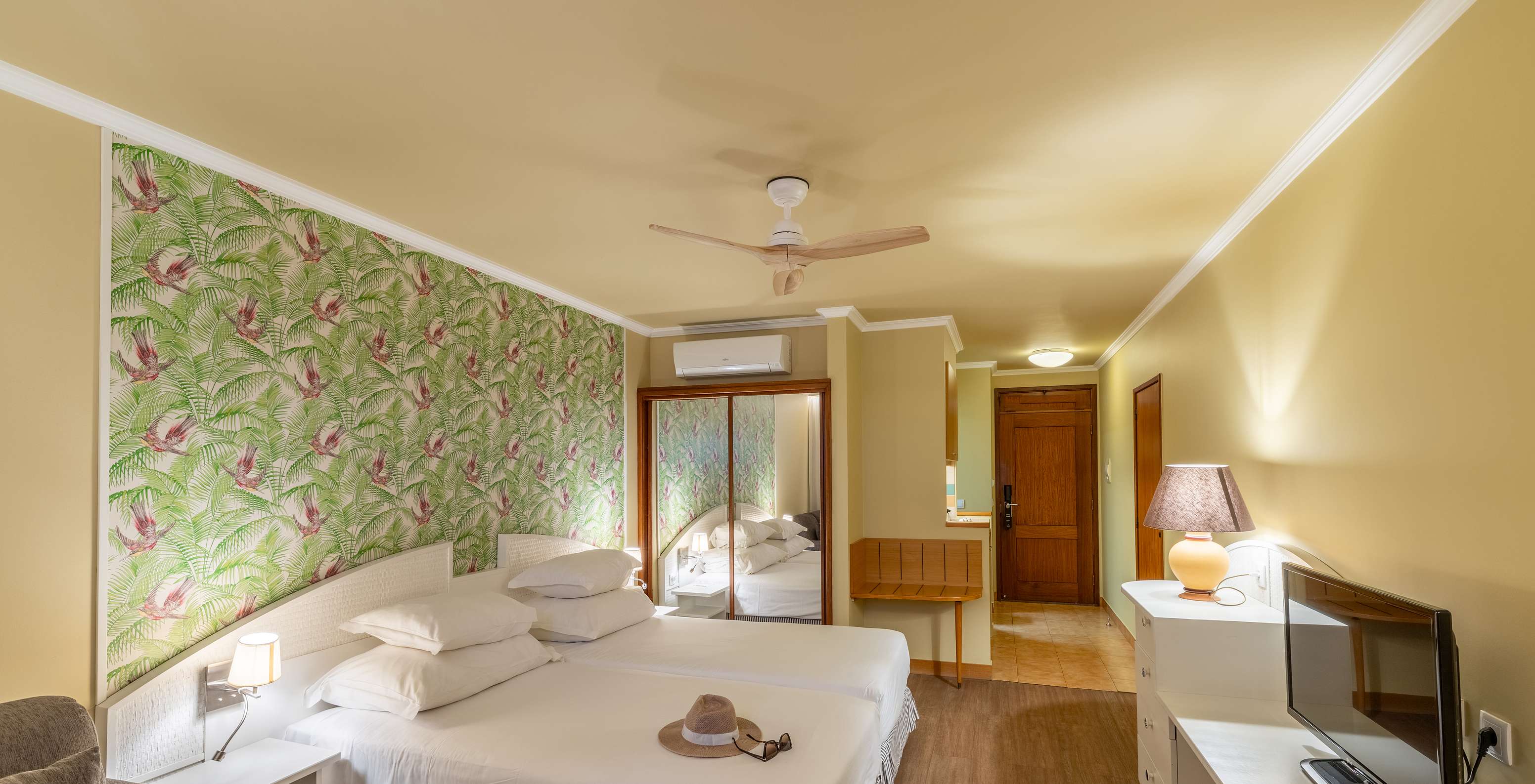 The Pestana Ocean Bay All Inclusive Premium Sea View has a double bed, palm tree wallpaper and a mirror