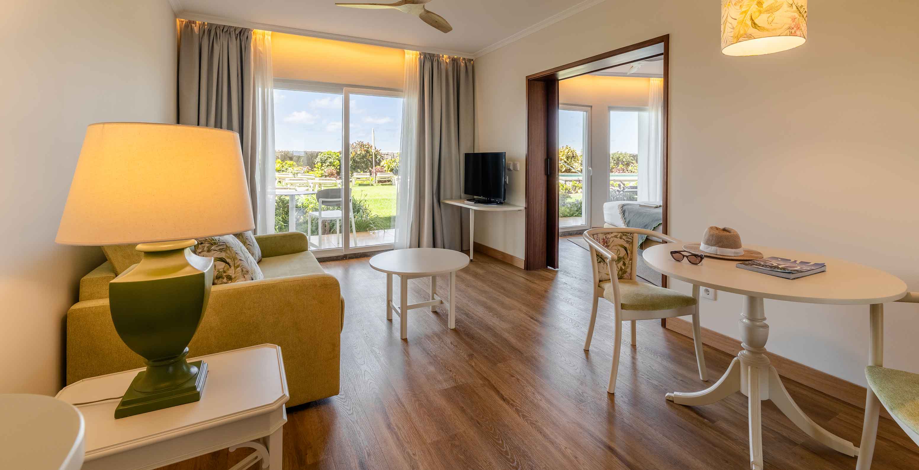 The Pestana Ocean Bay All Inclusive Junior Suite Sea View has a bright living room with a sofa, a coffee table, and a dining table