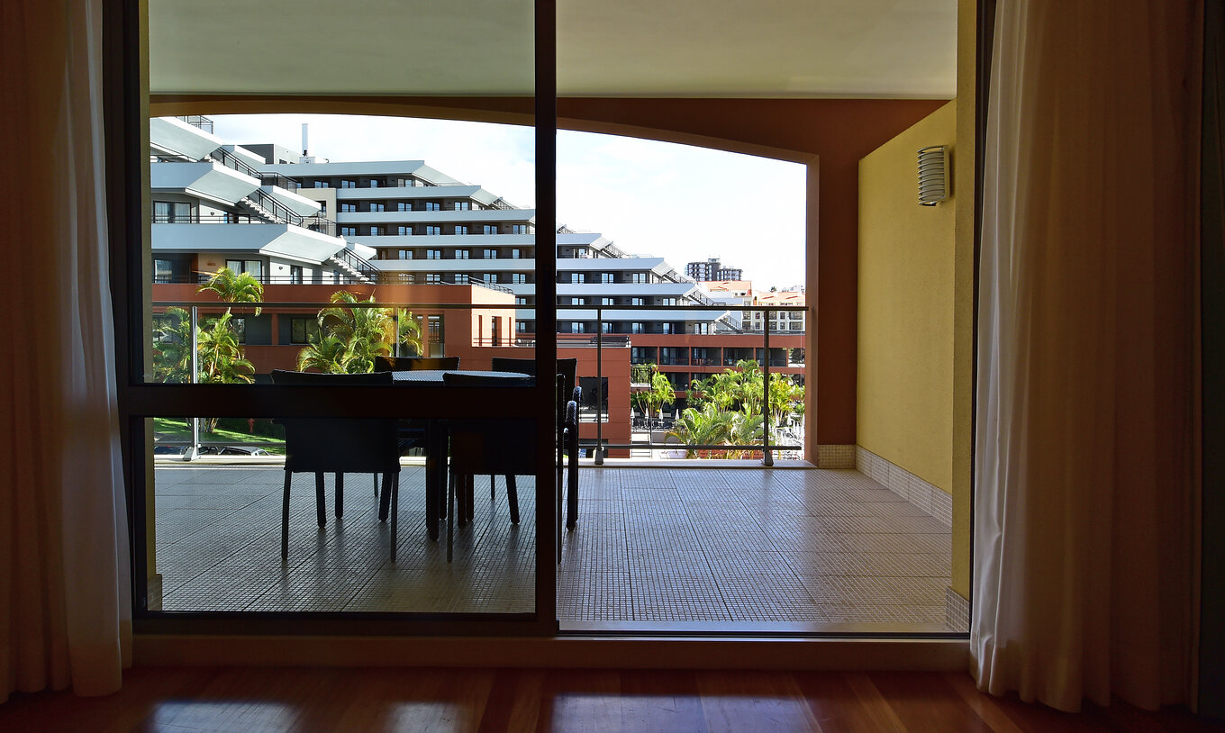 The Classic of Pestana Promenade has a spacious balcony with a dining table and a view of other rooms
