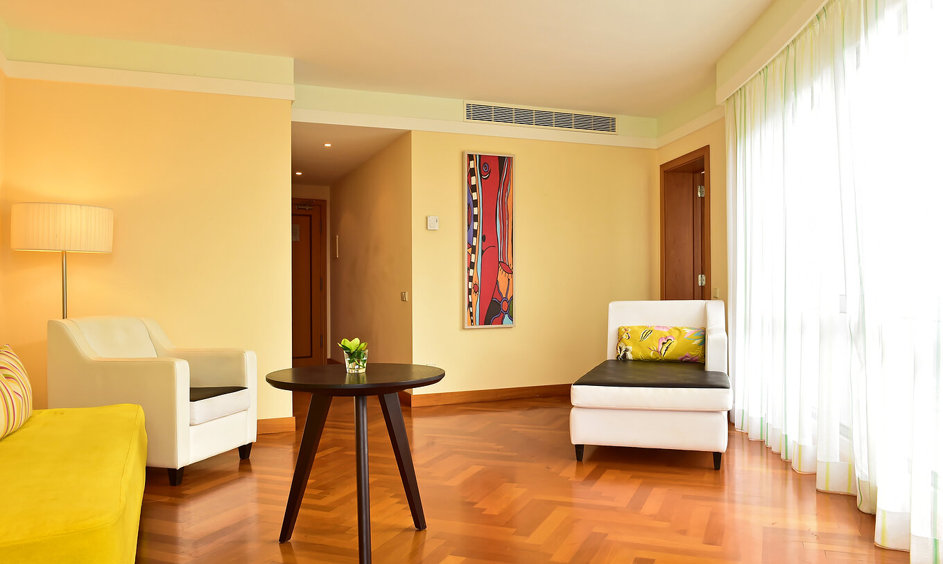 The Suite Sea View of Pestana Promenade has a living room with a large window, a green sofa, and two armchairs