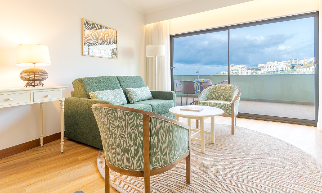 The Superior Lateral Sea View Suite at Pestana Vila Lido Madeira features a living room with sofa, armchairs, and balcony