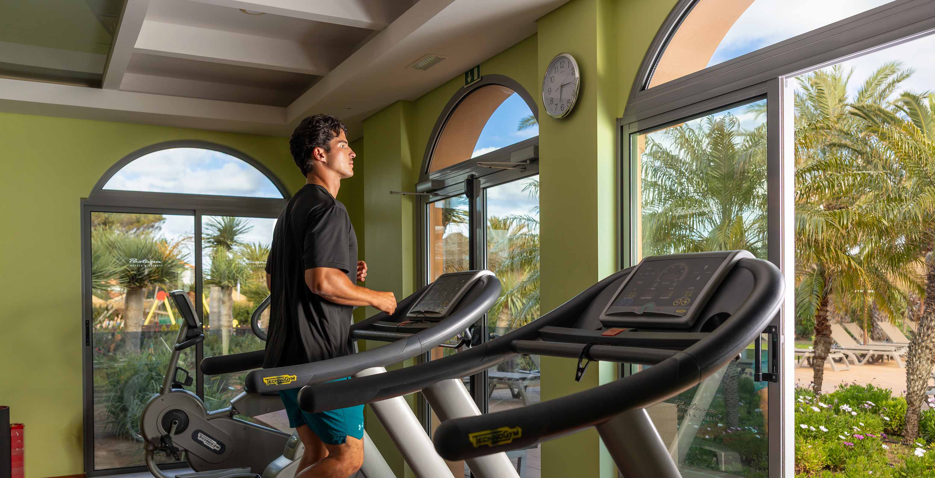 Guest using the treadmill in the gym at Pestana Porto Santo, in a room with a view of the garden